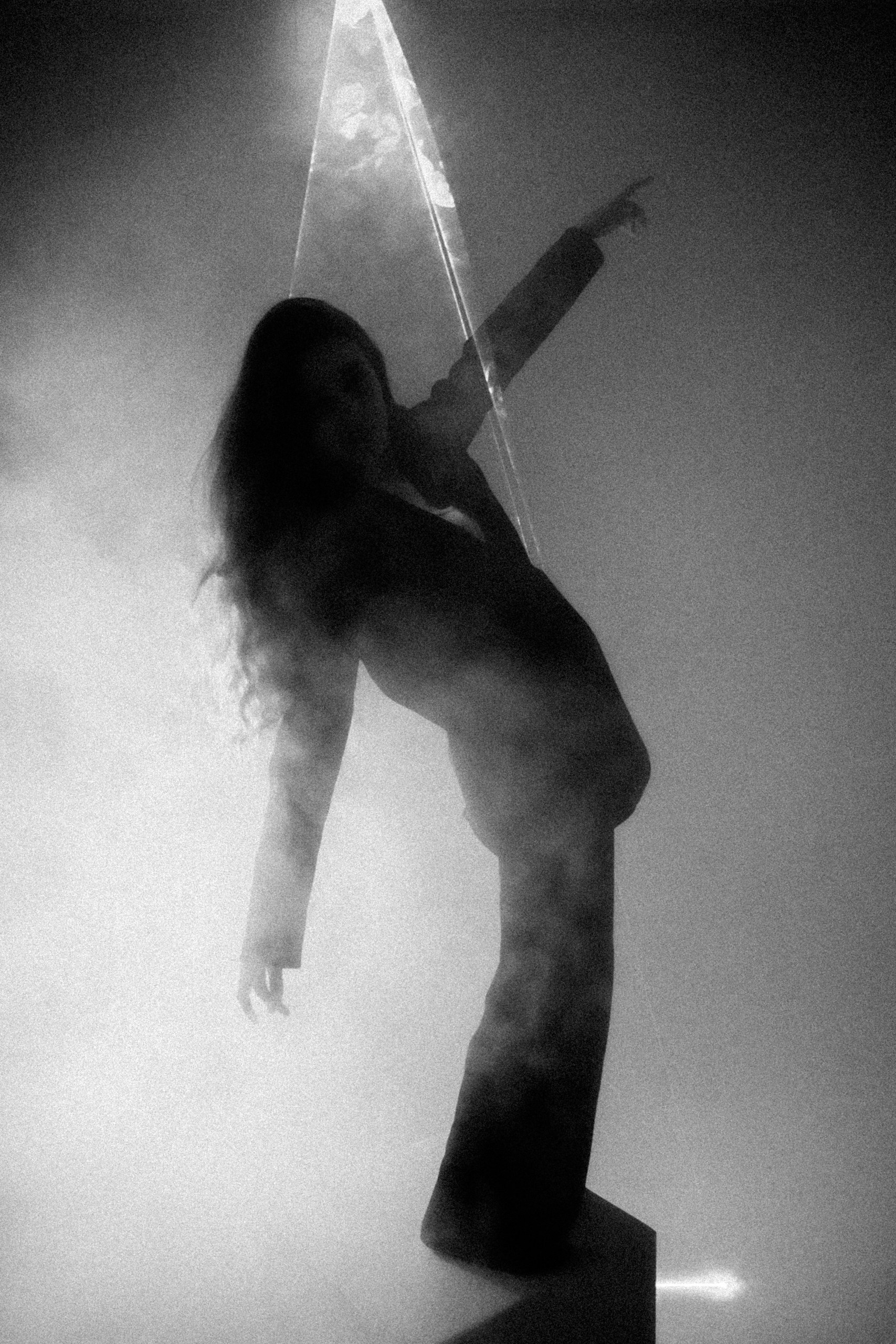 Экспериментальная художественная фотография: силуэт девушки в движении, стеклянная призма и световые лучи, чёрно-белое зерно