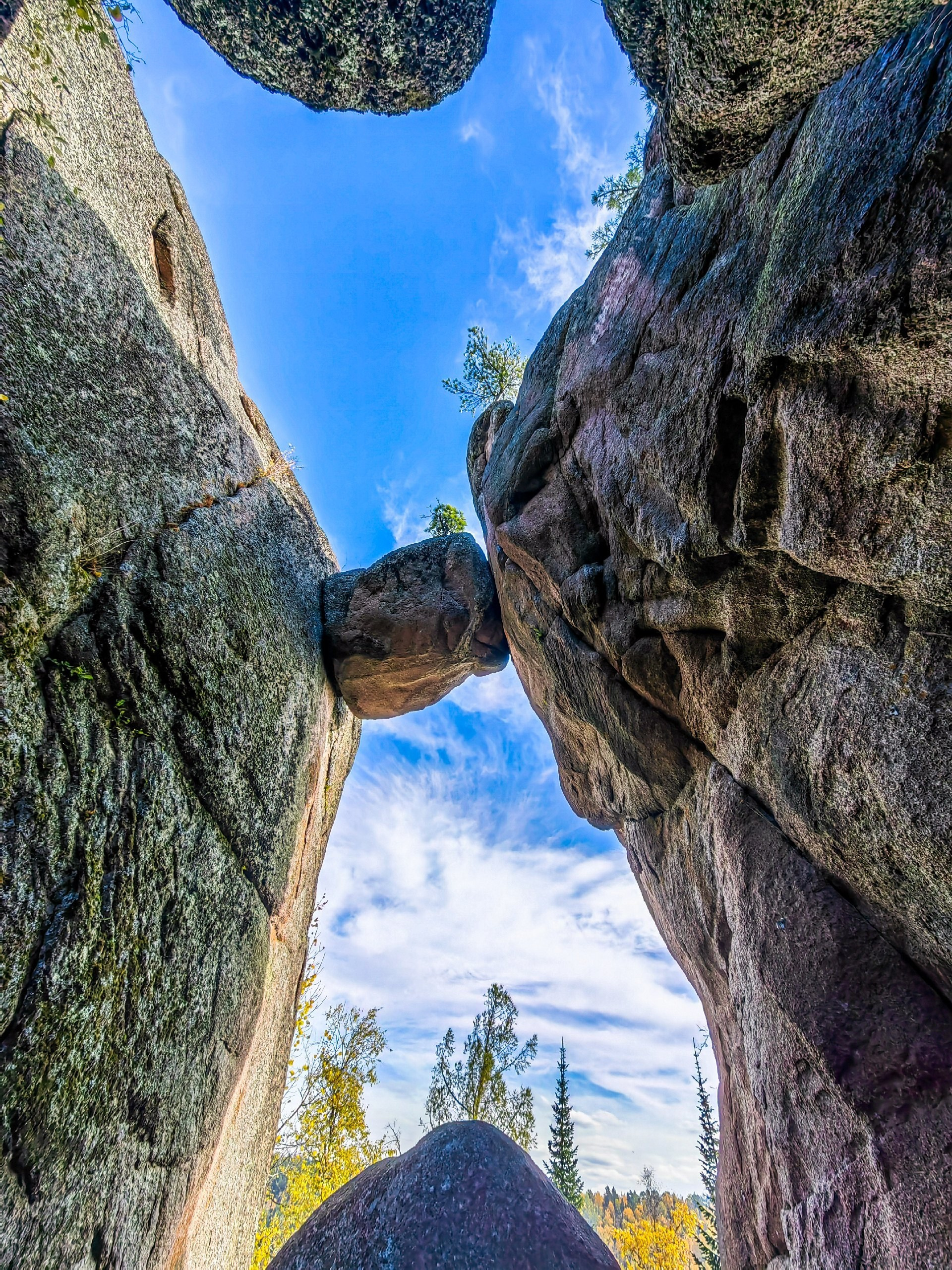 Путешествие в Красноярск и тайгу Столбов: валун застрял между двумя гранитными стенами, в просвете синее небо и облака. Пройдём узкими проходами между скал вместе с гидом, сколько стоит такой маршрут, скажу при бронировании.