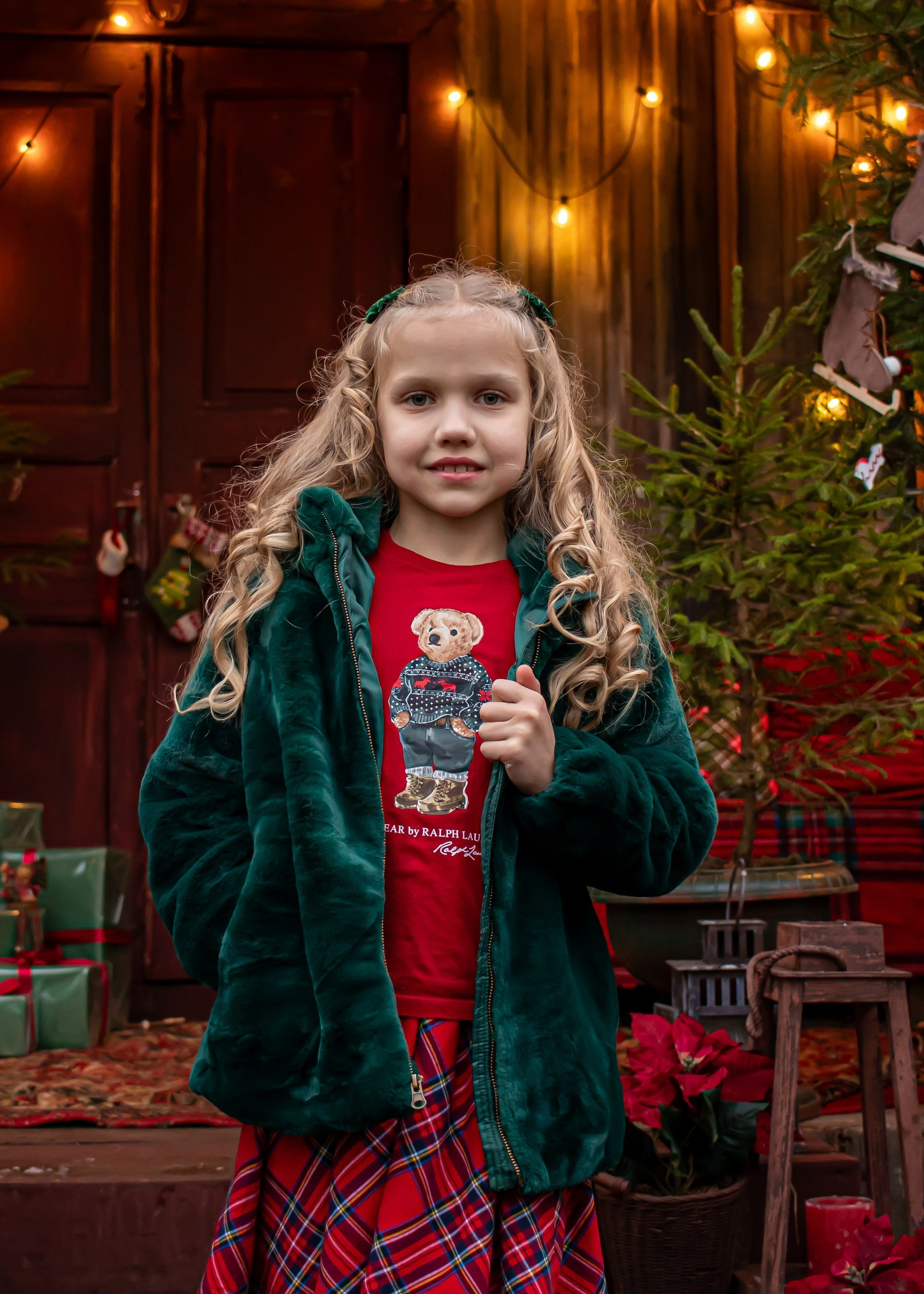 Девочка в зелёной шубке улыбается крупным планом среди ёлок и огоньков, новогодняя съёмка, фотограф Карасёва Елена