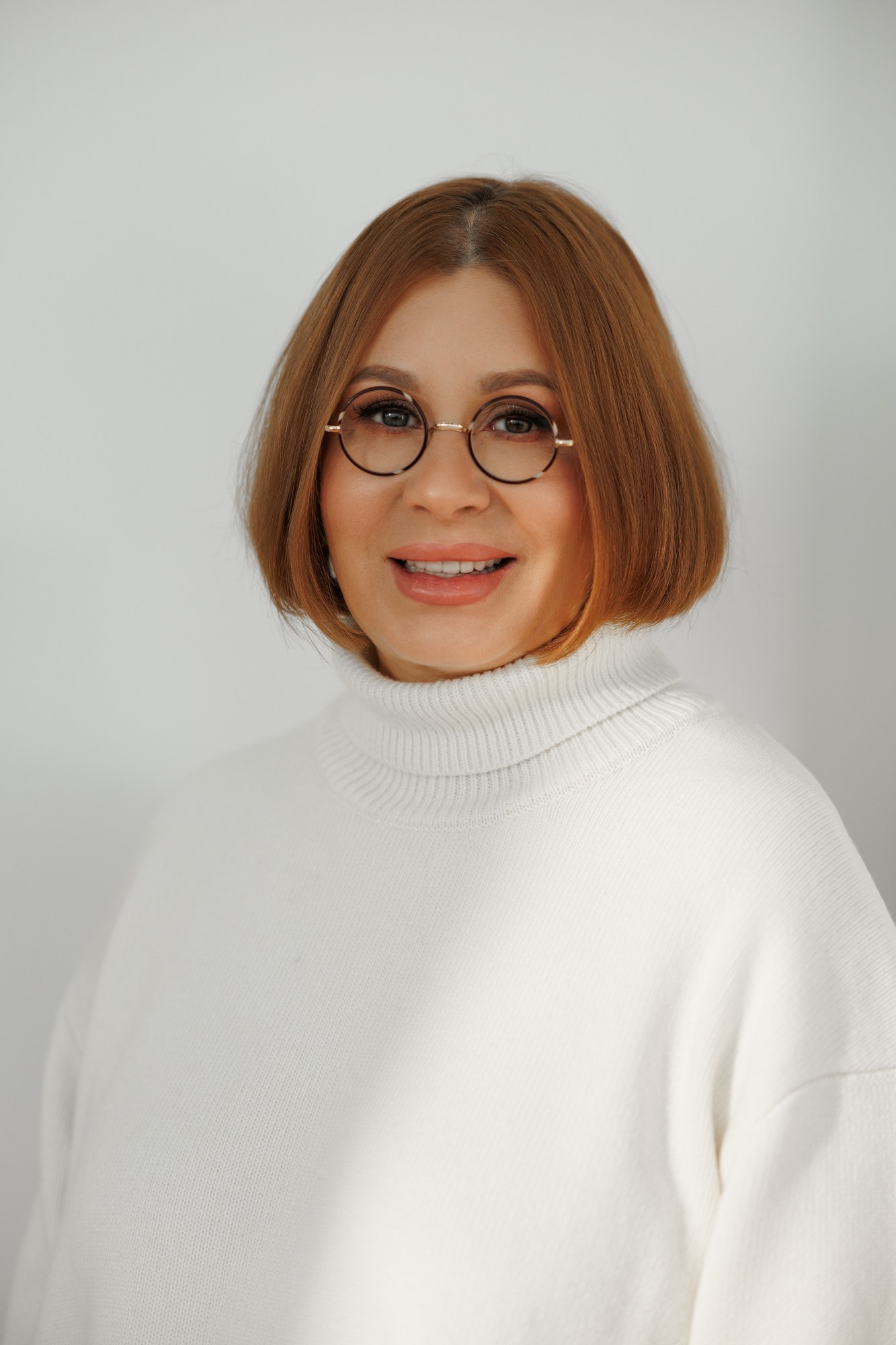 Фотография профессиональной юристки, специализирующейся на семейном праве, в деловой обстановке. На снимке изображена уверенная в себе женщина в элегантном костюме, с документами в руках, на фоне кабинета с книжными полками. Фото сделано для портфолио фотографа, специализирующегося на деловых и портретных съемках.