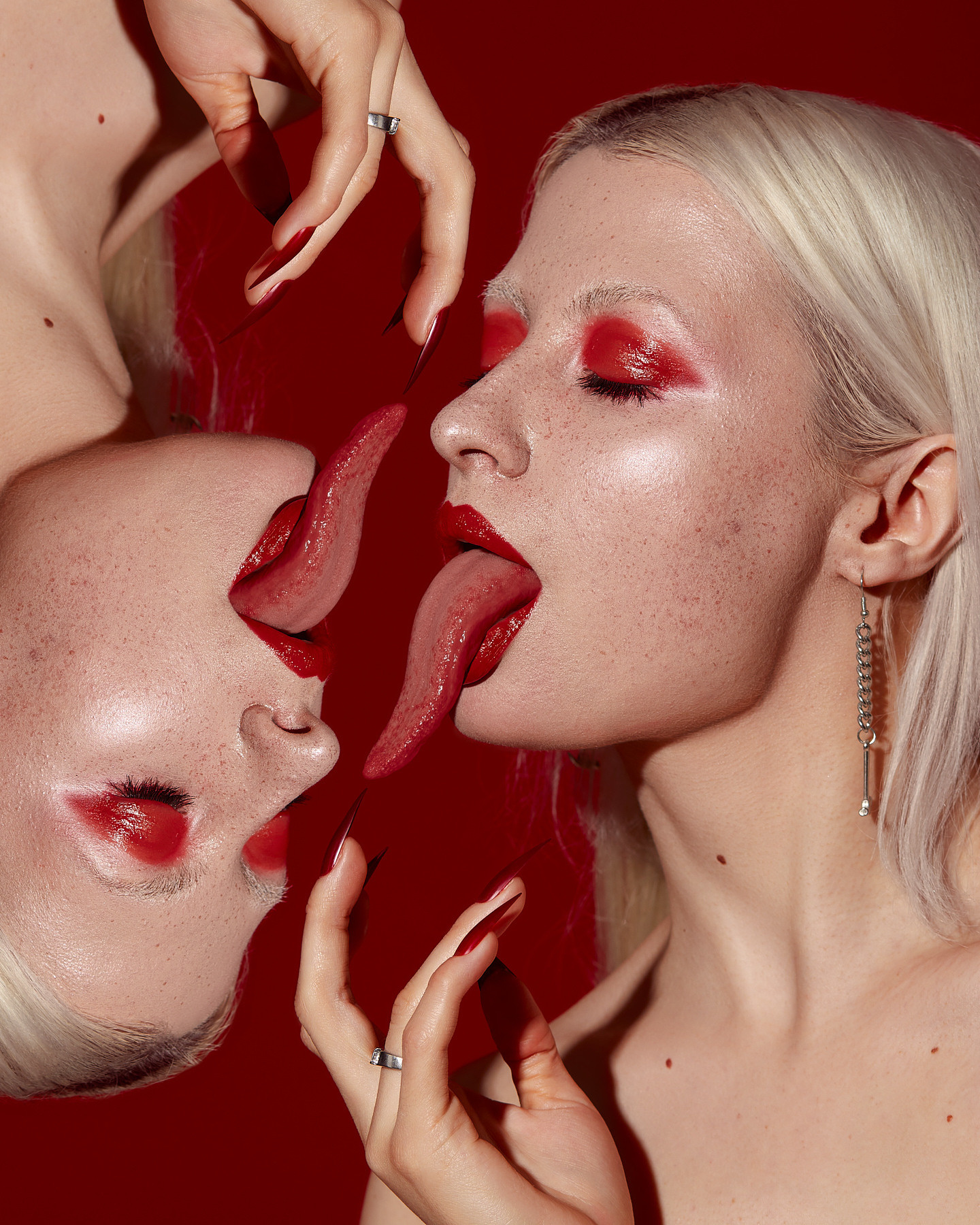 Творческая работа в которой отражает два зеркальных изображения, где модель тянет язык, создавая эффект симметрии. Фон выполнен в насыщенном красном цвете, что подчёркивает смелую и яркую концепцию работы