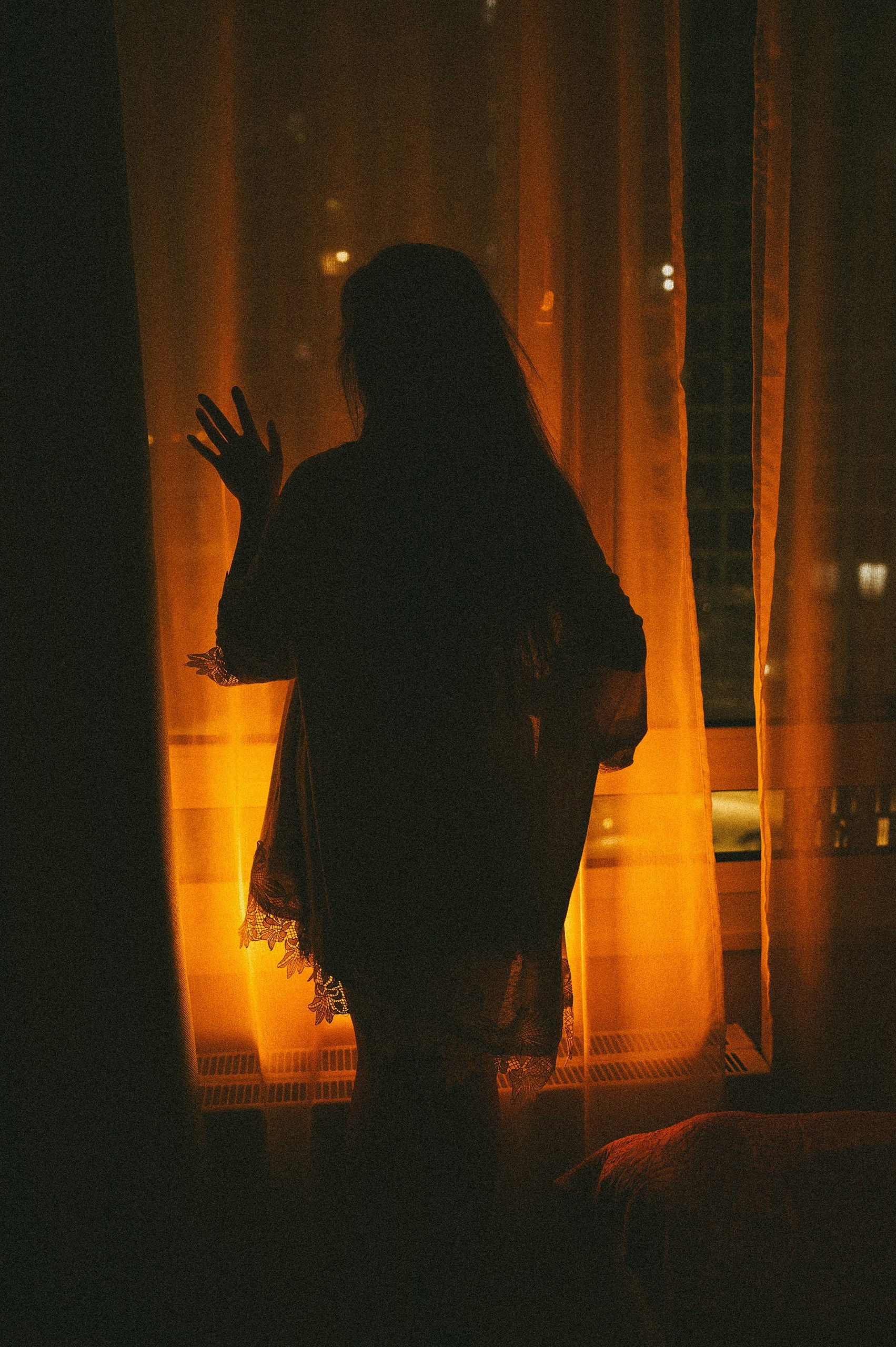 фотография силуэта девушки с цветным светом у окна ночью