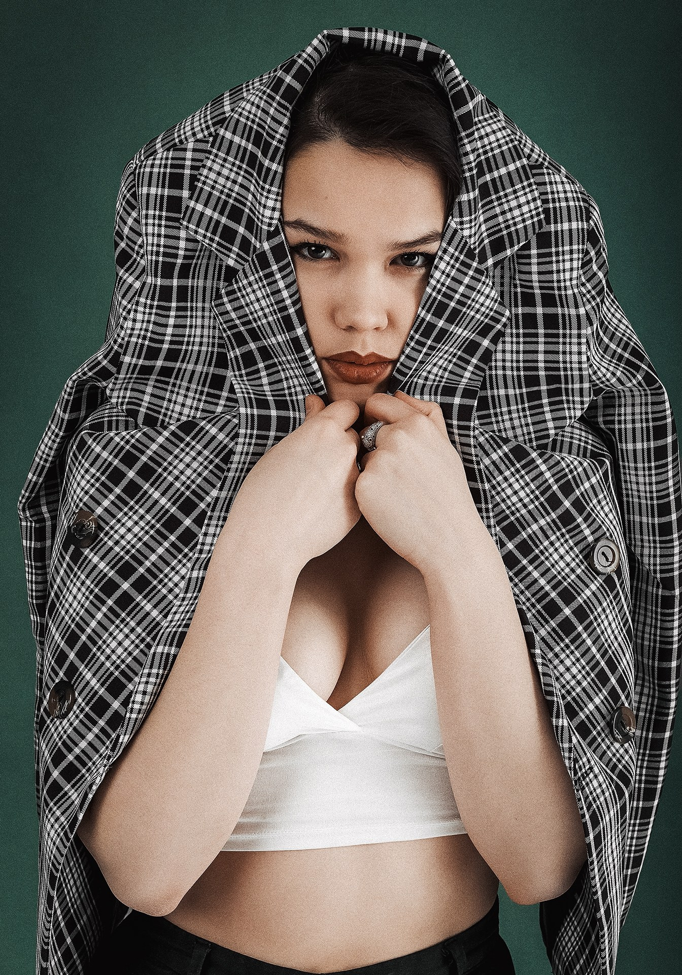 Девушка позирует с пиджаком на голове в студии, съемка в пиджаке на зеленом фоне