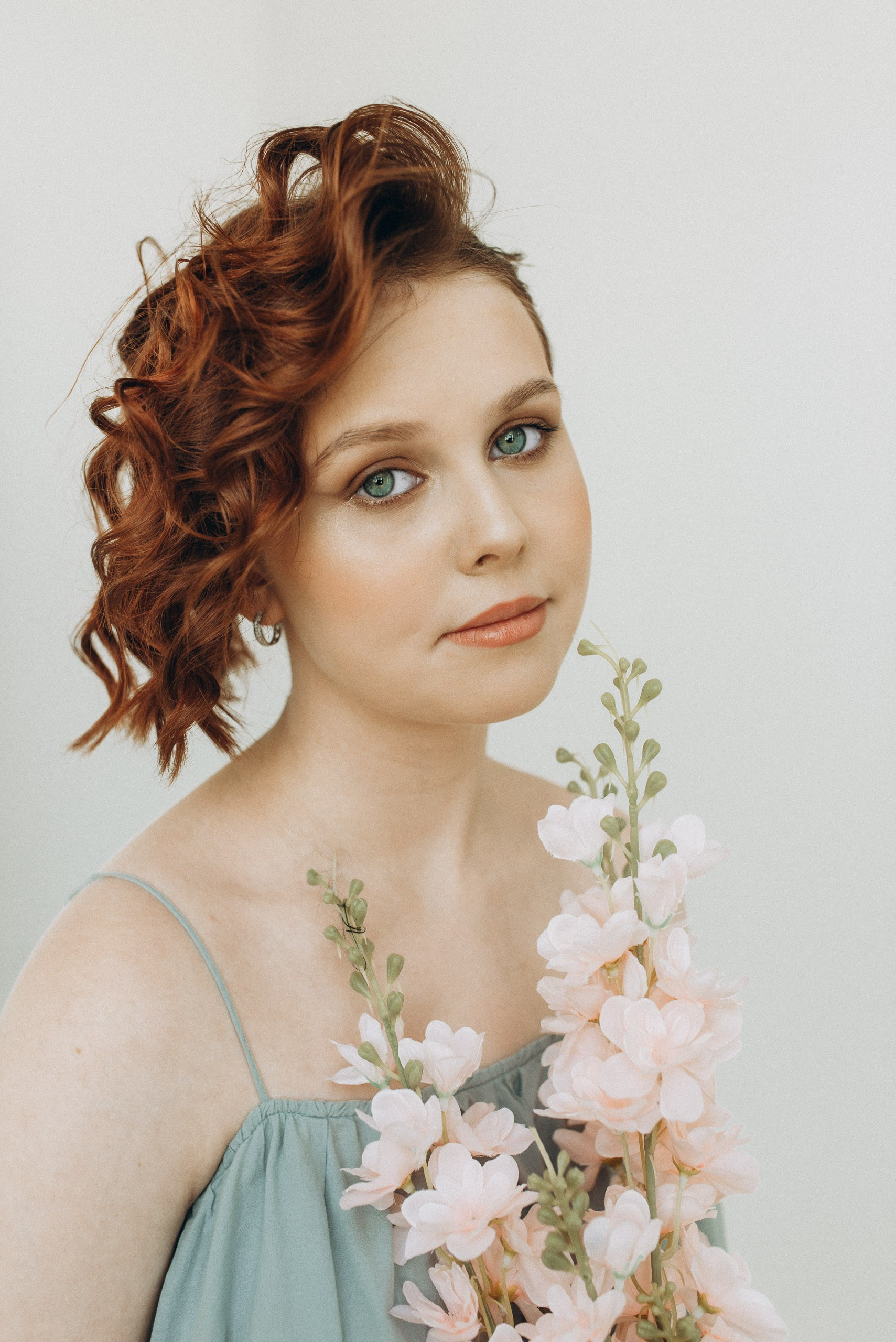 Крупный план девушки с зелеными глазами и нежно-розовыми цветами. Естественная ретушь и мягкий свет. Фотограф Василий Дан