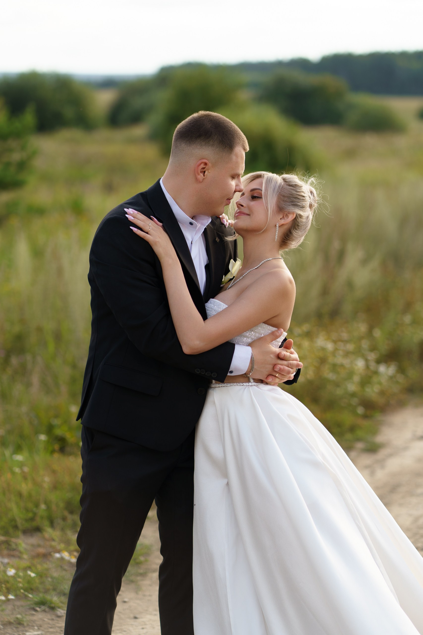 Счастье в объятиях: молодожёны на фоне зелёного пейзажа, их поза полна нежности, а взгляды говорят больше слов | портретная фотосессия Екатеринбург