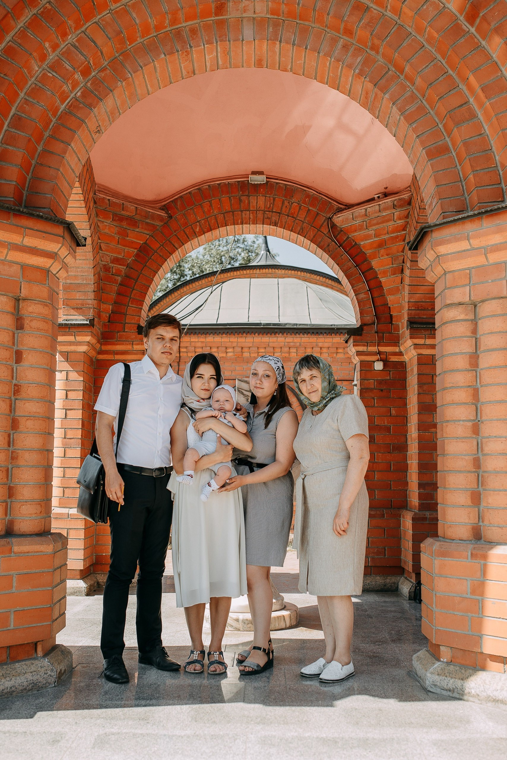 Профессиональная фотосъемка крещения, групповое фото семьи с бабушкой у входа в собор.