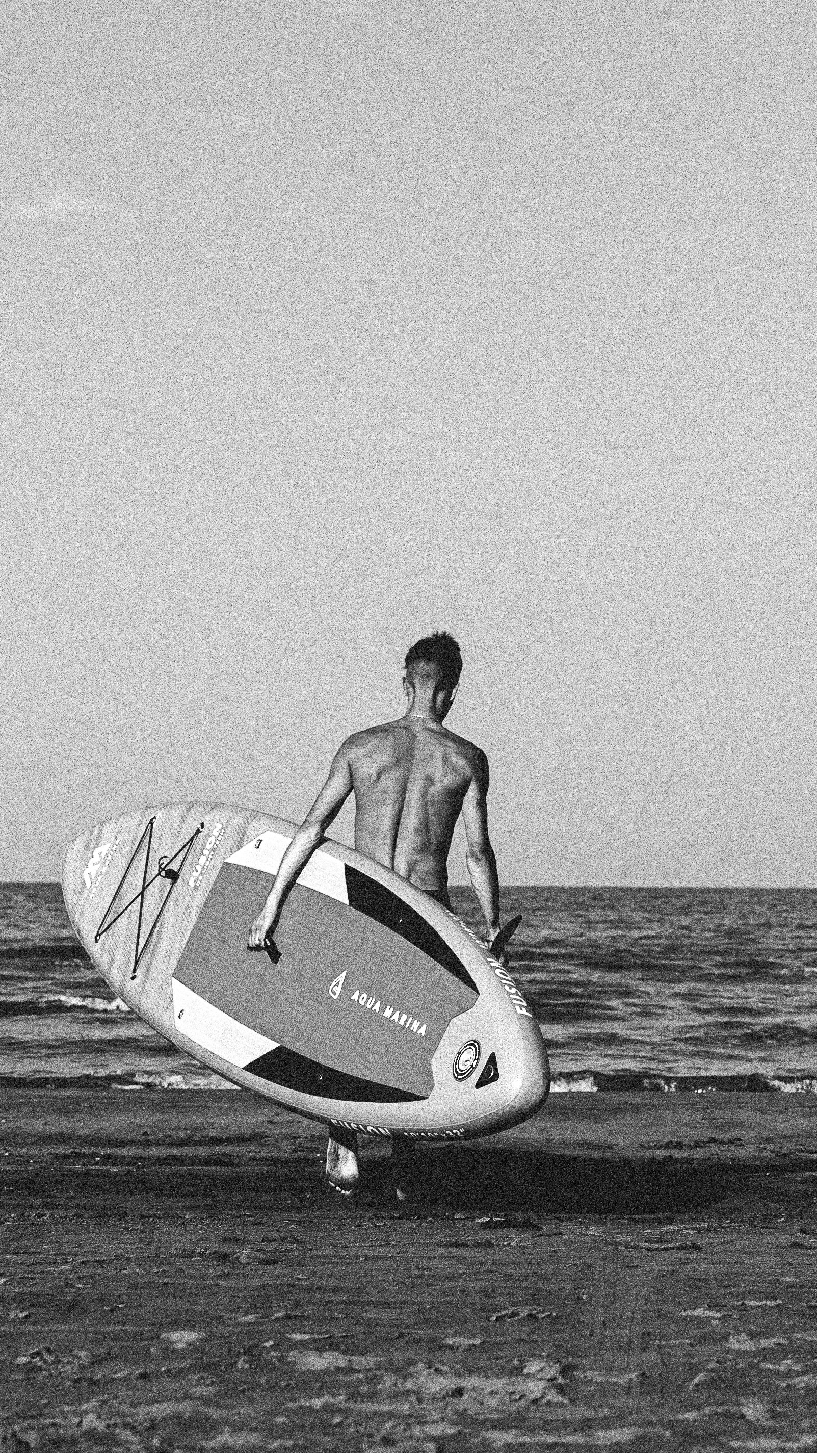 Мужчина с sup-board Aqua Marine идет к морю