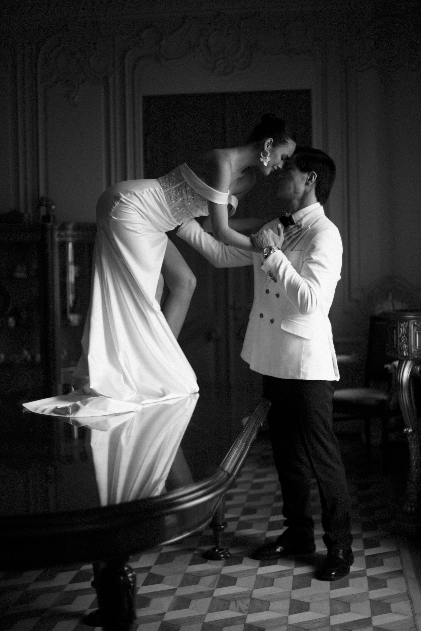 Чёрно-белая сцена: жених и невеста на столе в зале с лепниной — свадебная фотосессия в Trezzini Palace Hotel СПб
