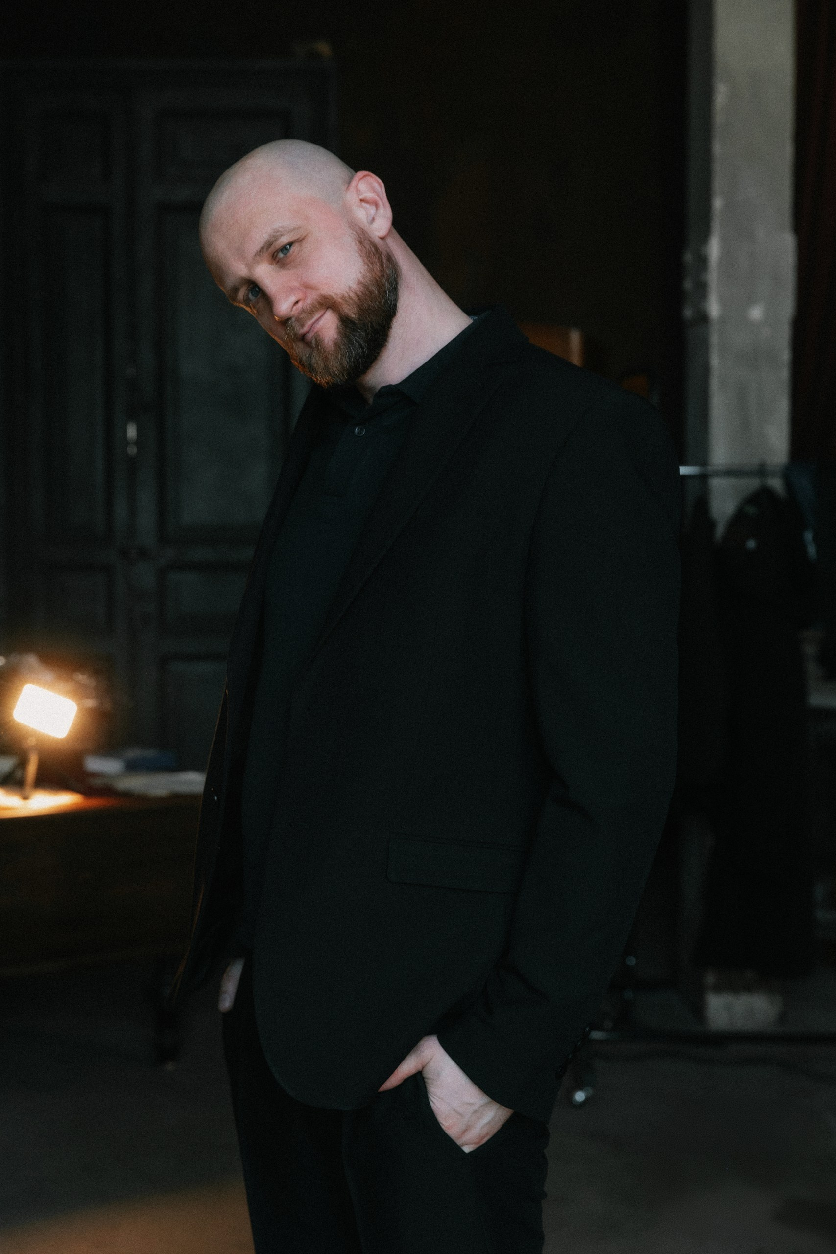 Деловой мужчина в чёрной одежде опирается о дверной проём — стильный портрет для сайта эксперта, Санкт-Петербург