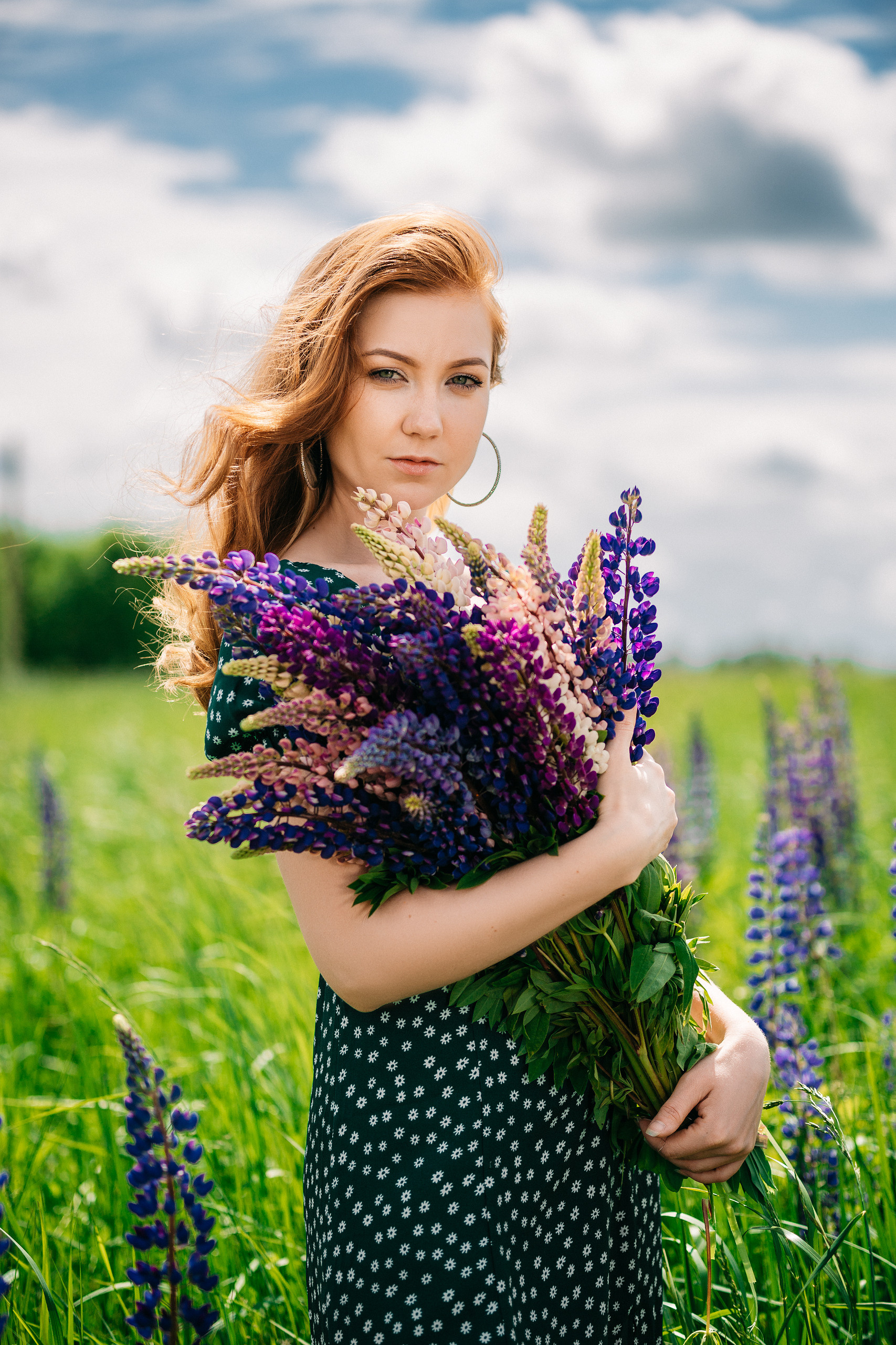 Девушка в зеленом платье с большим букетом люпинов