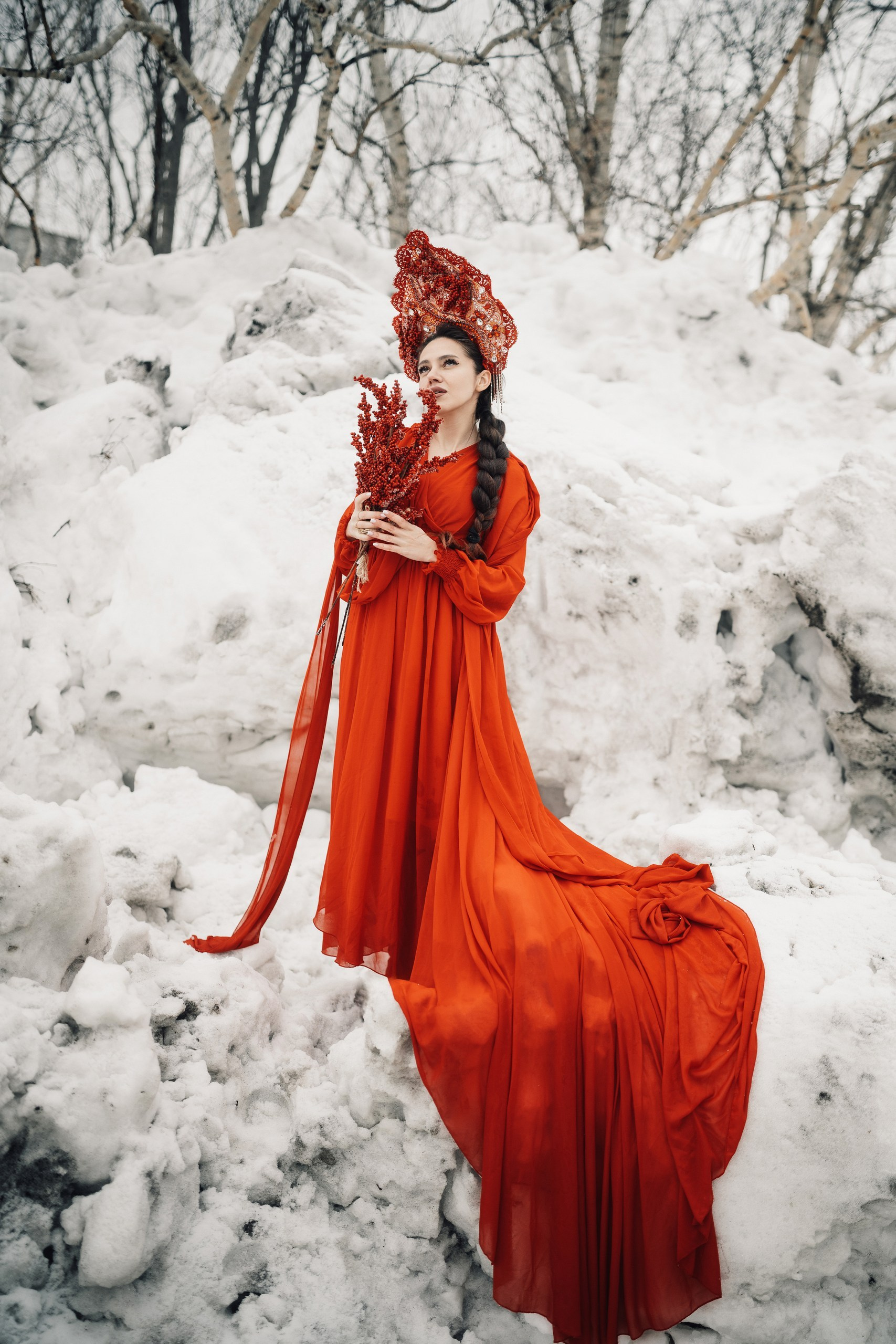 Девушка в красном платье в образе весны на фоне тающего снега в городе, уличная фотосессия весной, контрастный художественный портрет