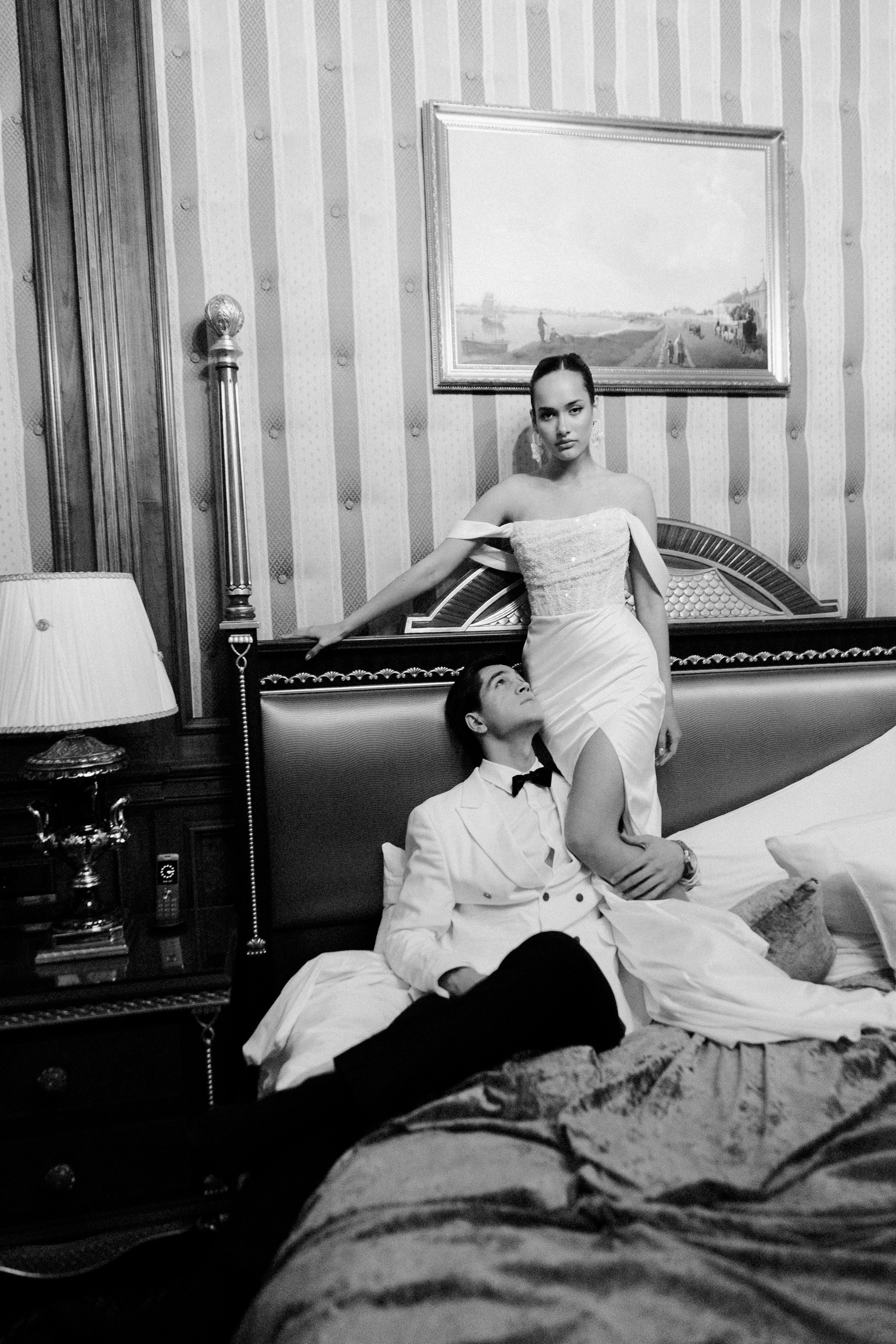Чёрно-белая сцена: жених и невеста сидят на кровати — свадебная история в винтажном интерьере Trezzini Palace Hotel