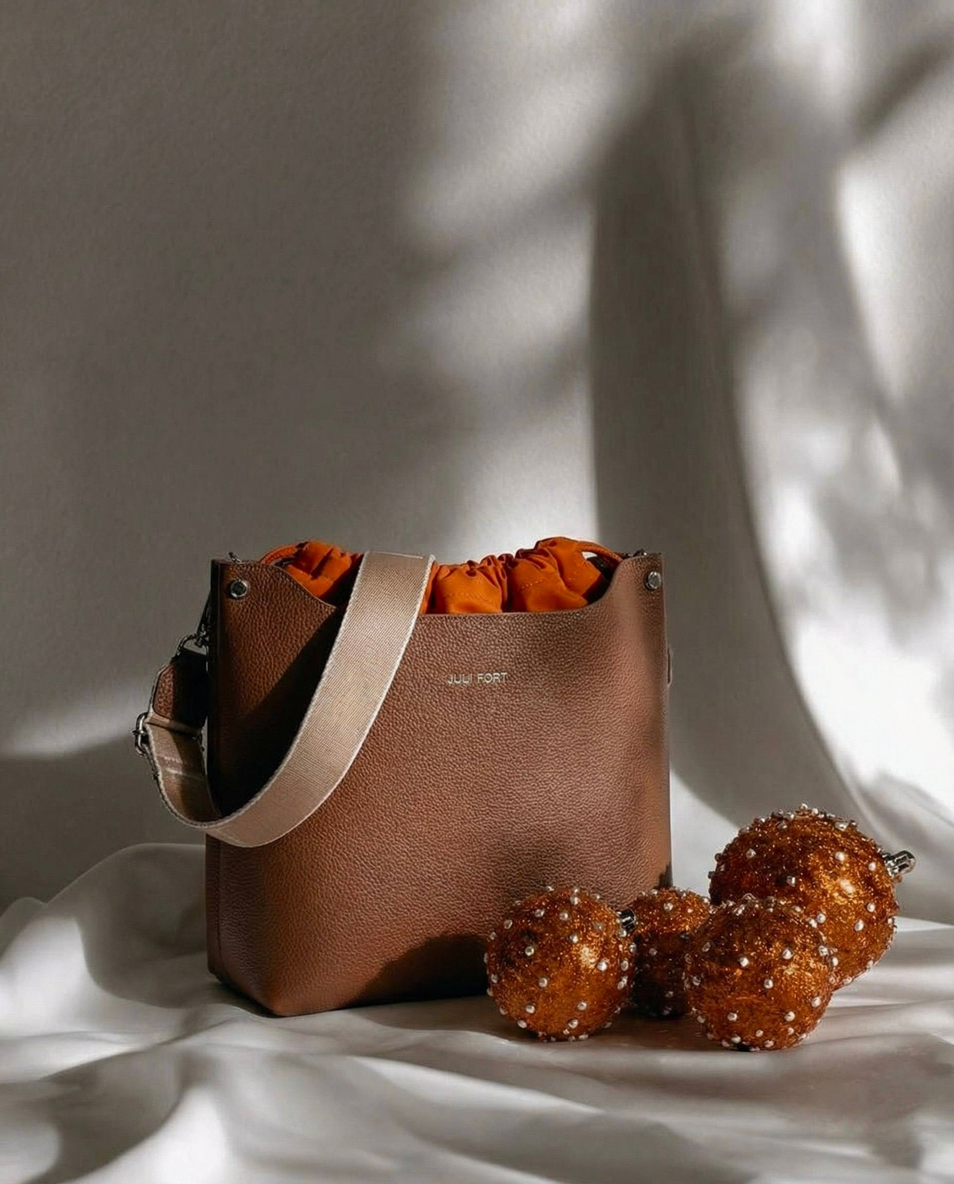 Предметная ии фотосессия сумки -коричневая сумка на белом фоне с рыжими шарами