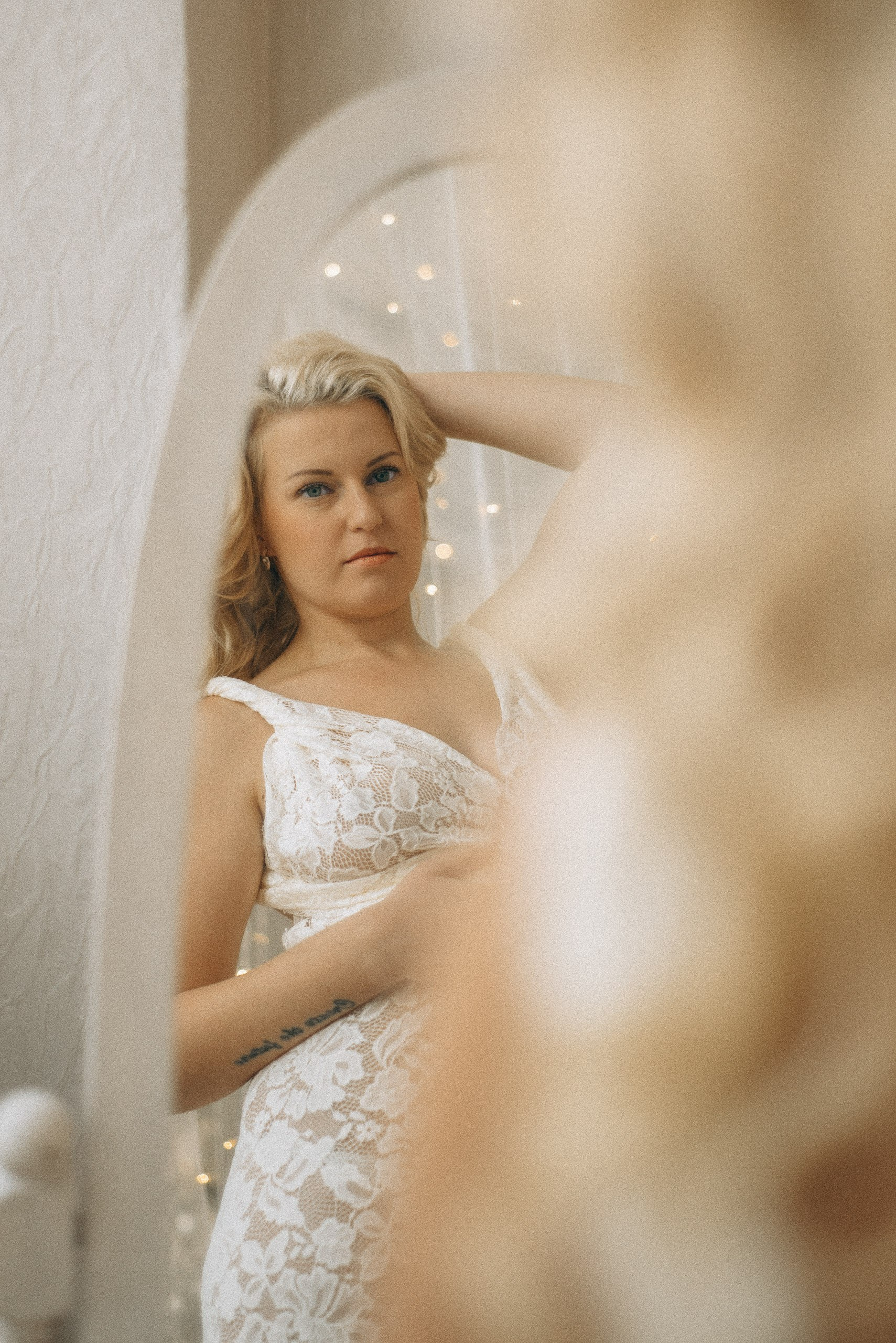Чувственное отражение Натали Каролин в овальном зеркале. Блондинка в белом кружевном платье, мягкий свет от гирлянд на фоне. Эстетика бохо-будуара, фотограф Василий Дан, Новосибирск