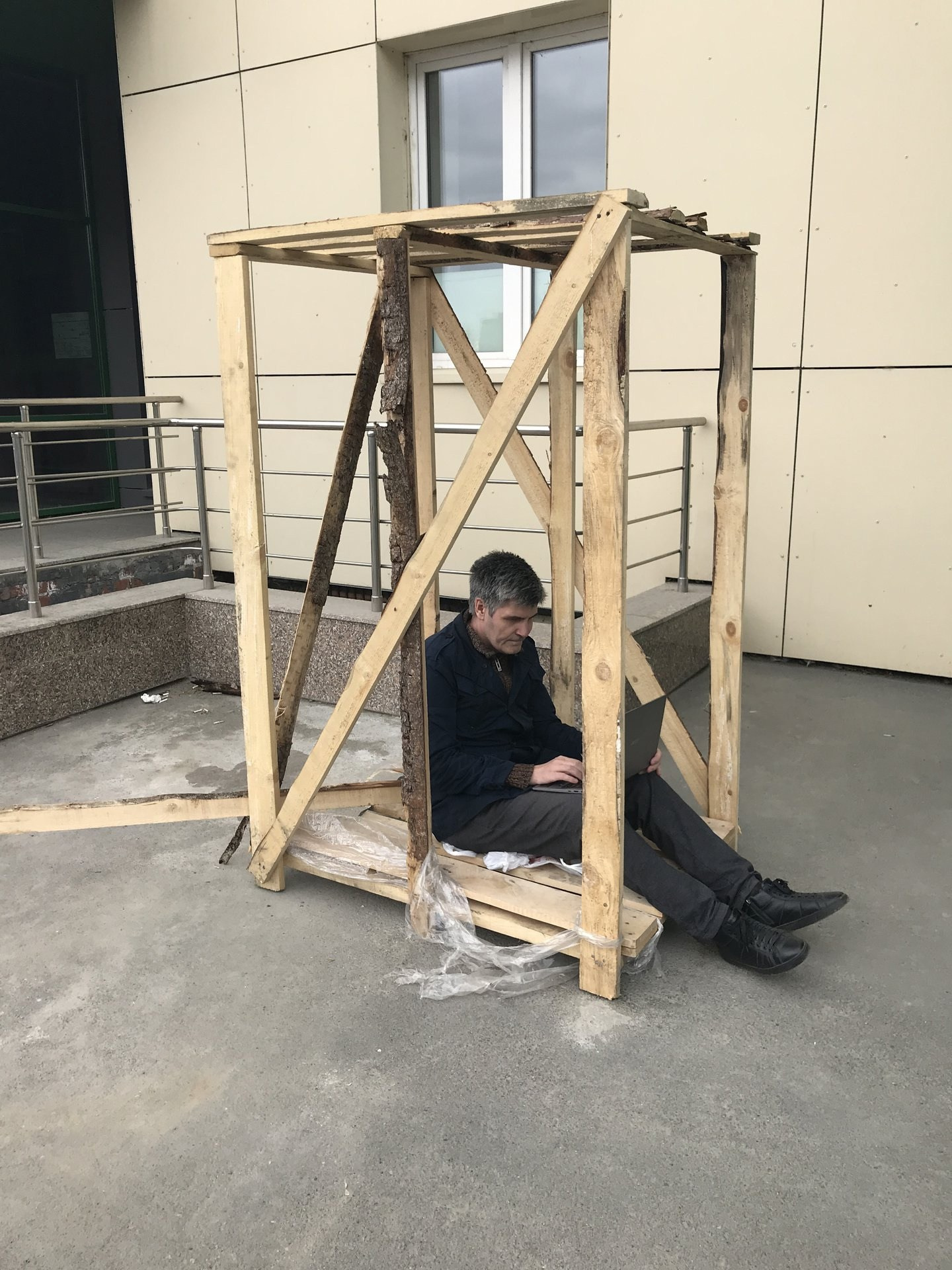 Художник в клетке с ноутбуком, у входа в продуктовый магазин, перформанс.