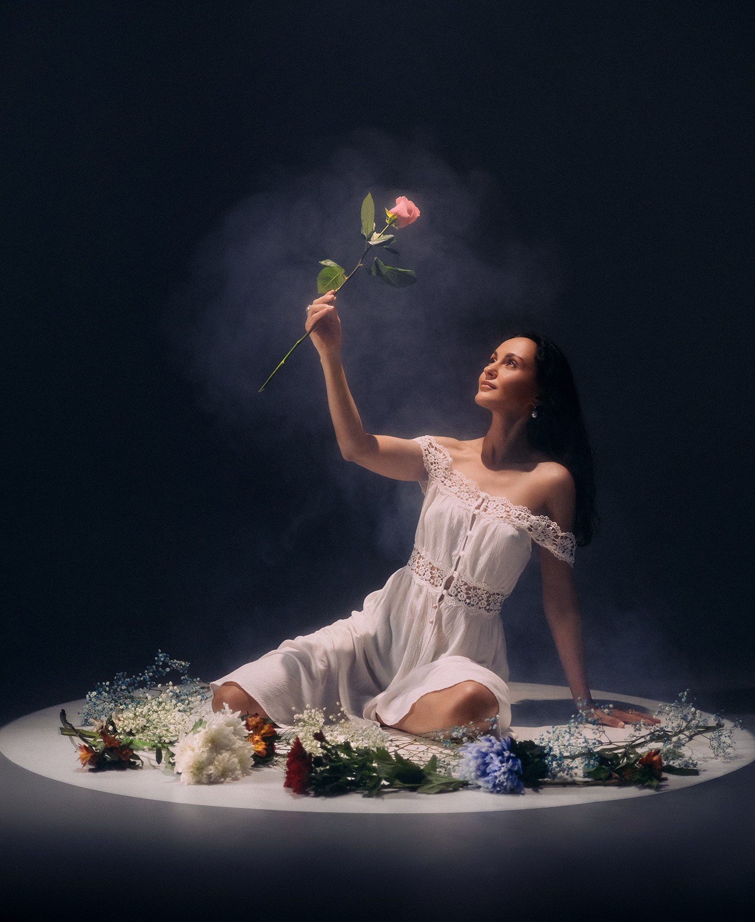 Девушка сидит в окружении цветов в руке держит цветок в белом платье. Съемка с цветами Казань
