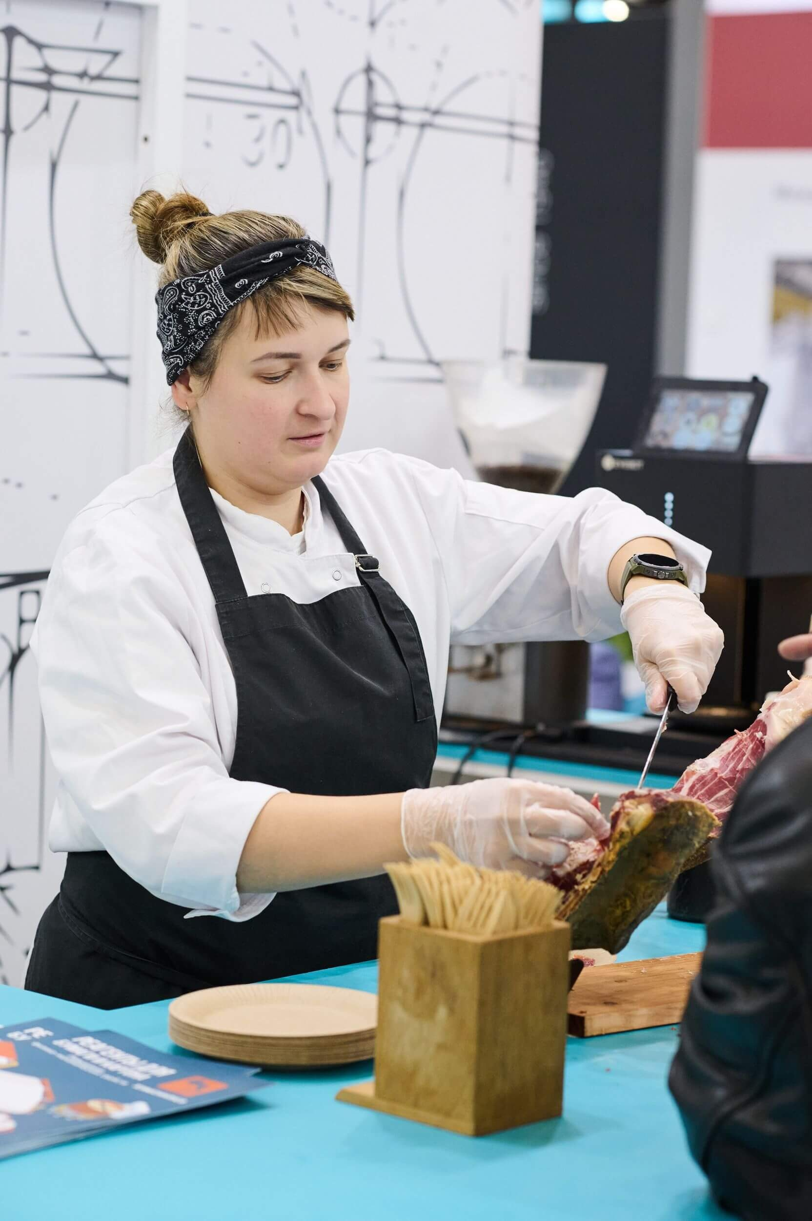 38. Девушка нарезает хамон на выставочном стенде.