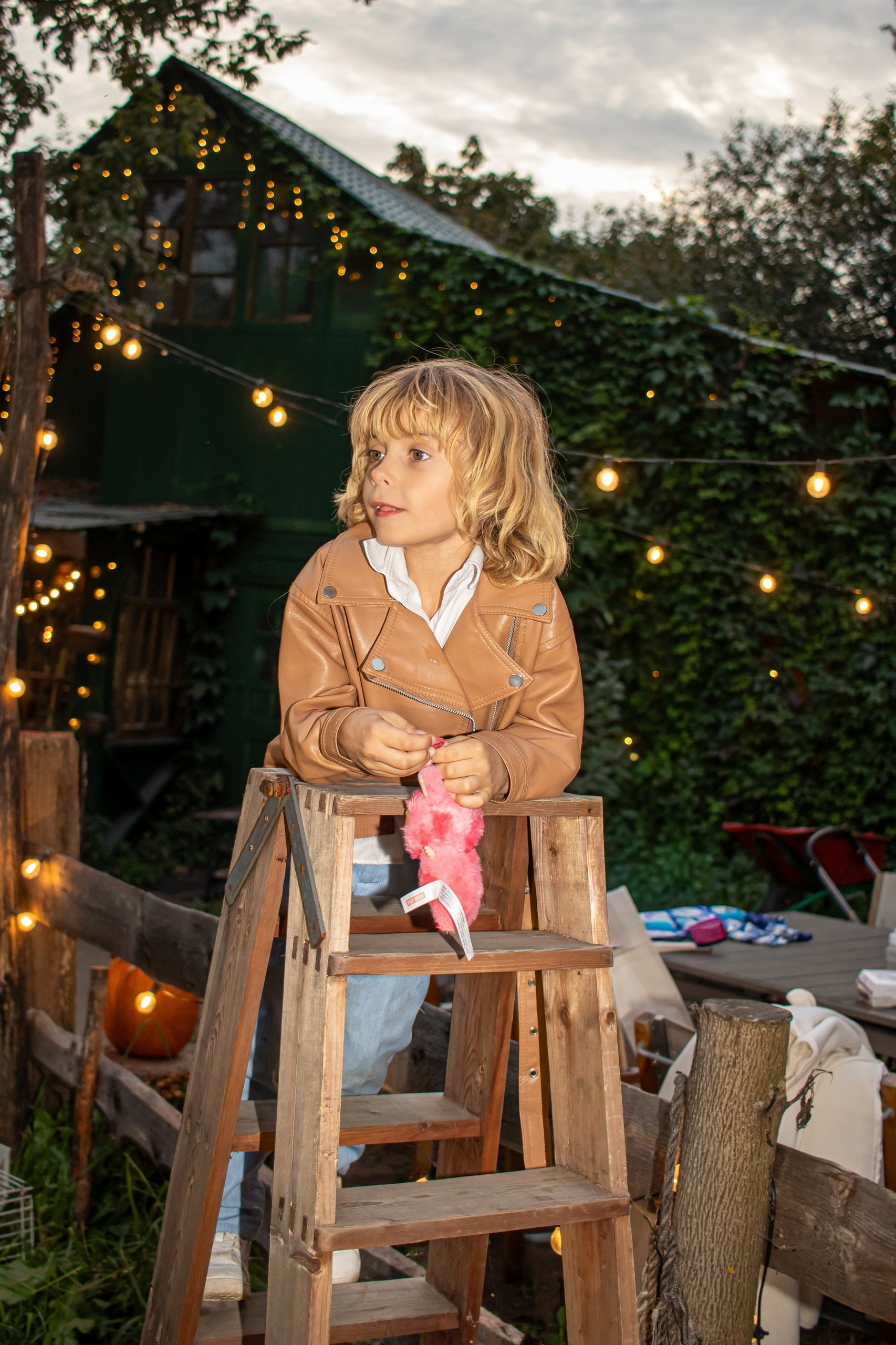 Ребёнок сидит на лестнице с игрушкой среди вечерних огоньков — тёплая детская съёмка, фотограф Карасёва Елена