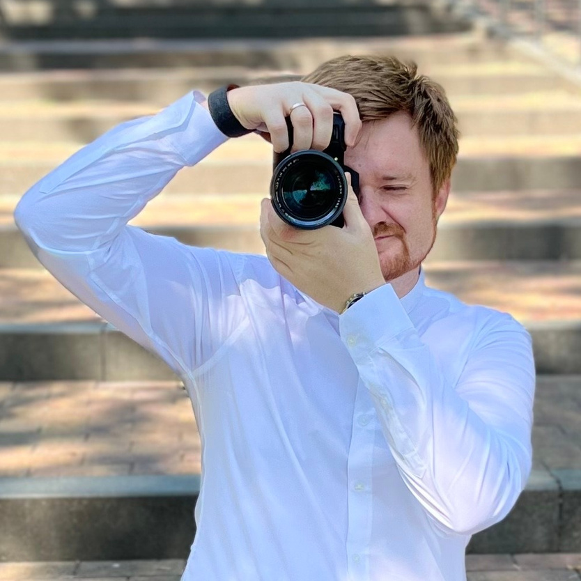 Фотограф Кирилл Ситнов RedGeek в парке с камерой в руках.