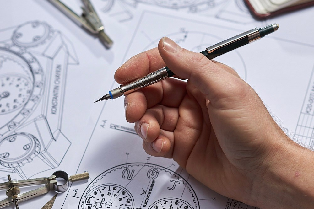 Hand with a pencil over a blueprint and drawing instruments - photographer Andrey Dunin