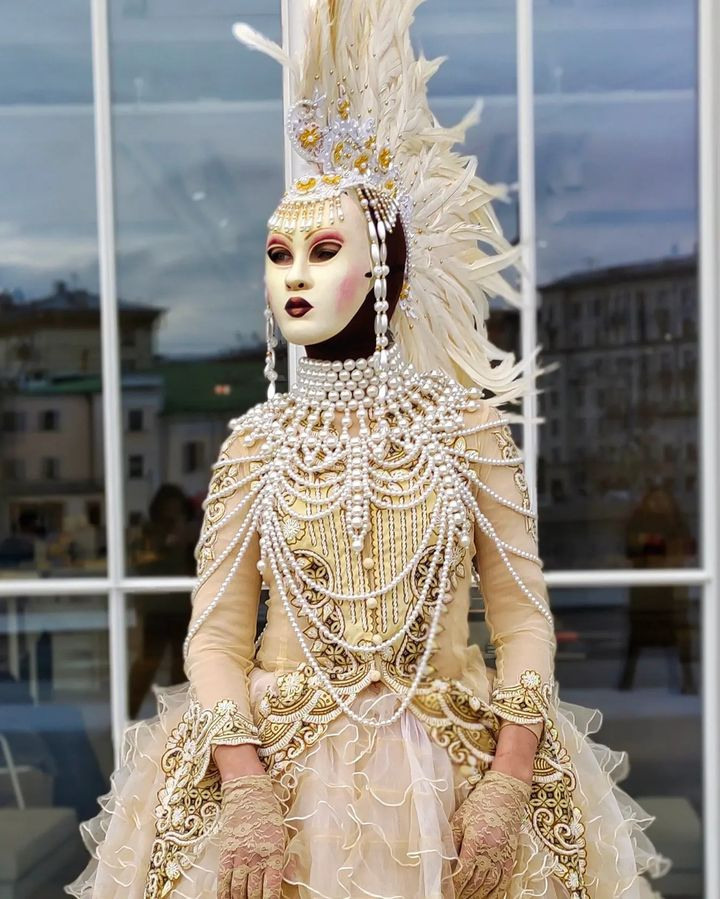 Мим в образе белой Вороны с маской на лице на встрече гостей у ресторана.