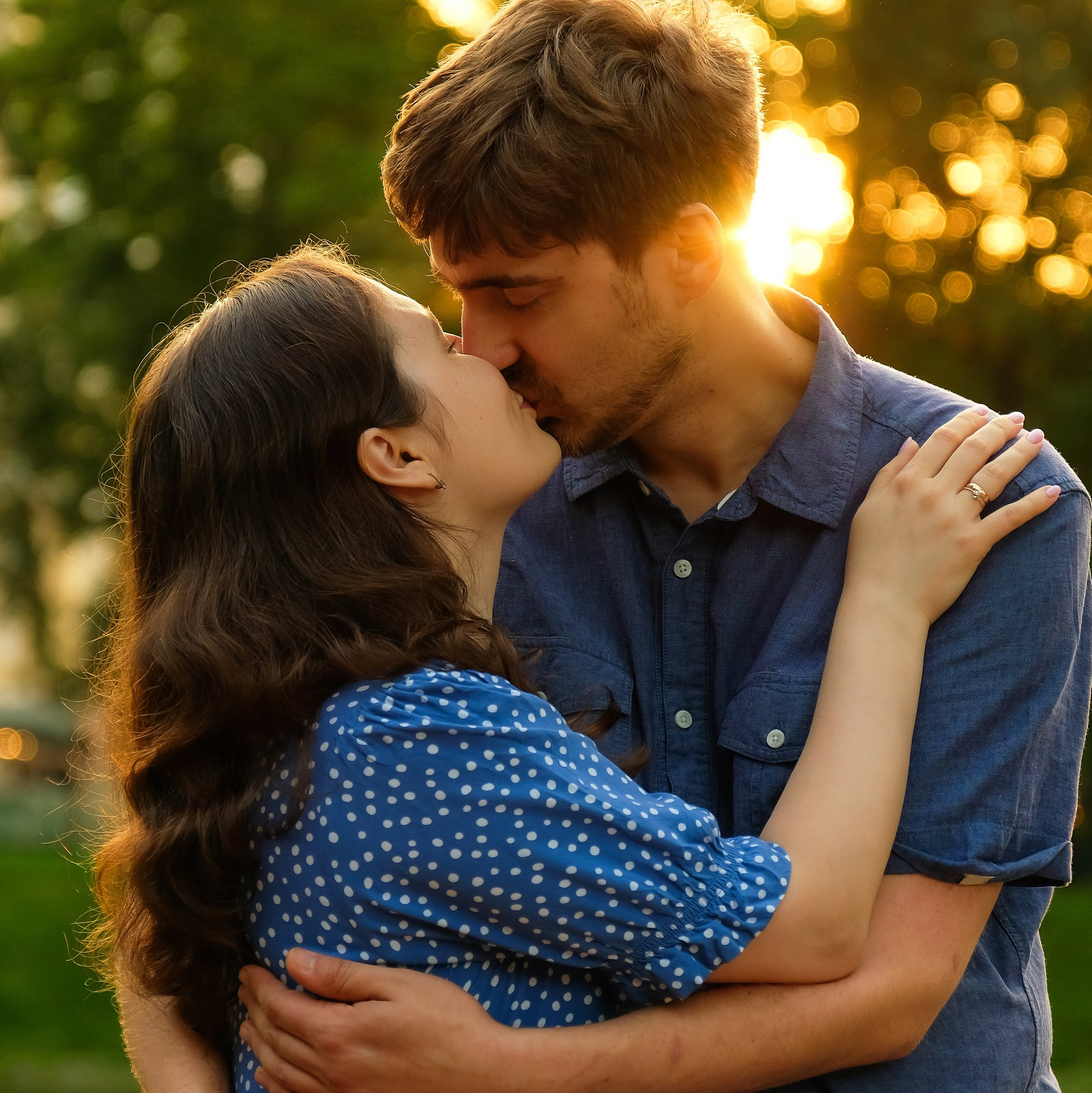 Пара целуется на фоне заката в парке