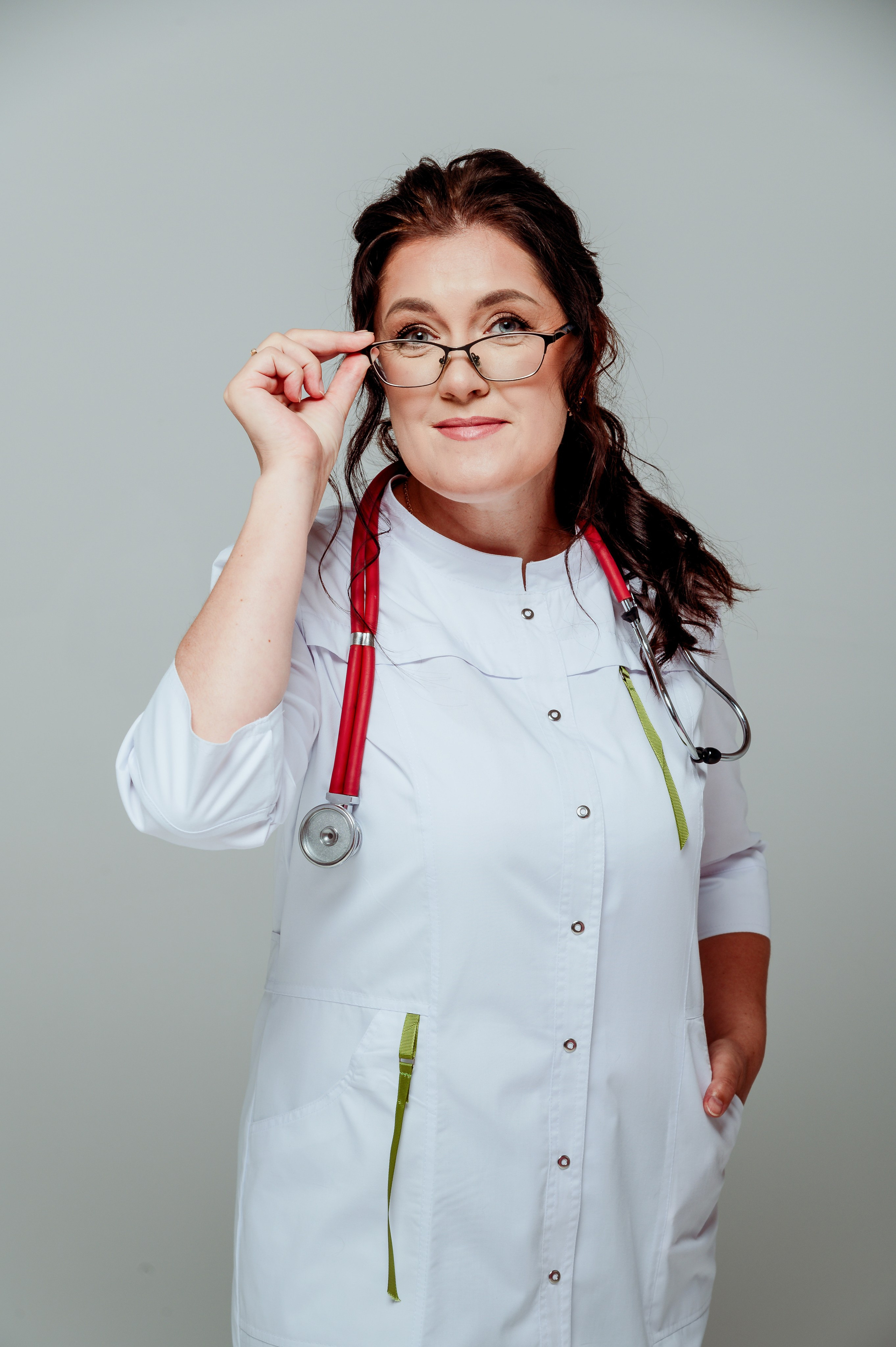 Business portrait of a female doctor in a white coat with a stethoscope on a grey background in Astana