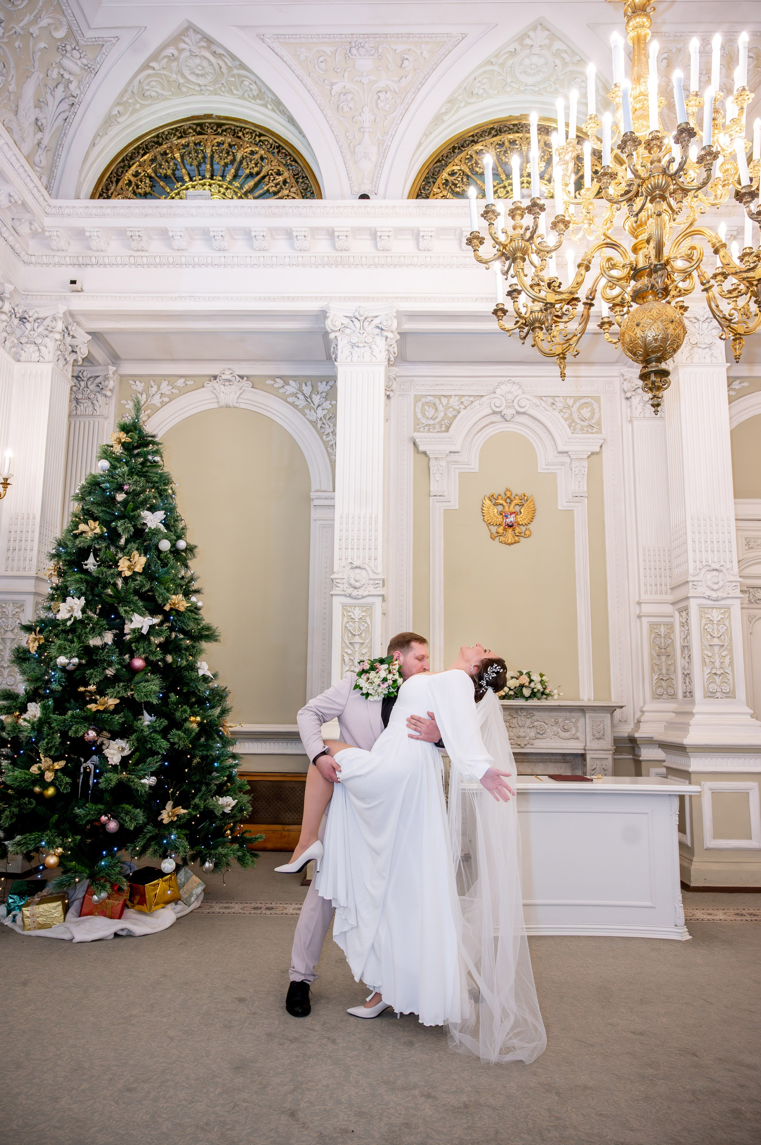 Жених будто в танце наклоняет невесту в зале торжественной регистрации Первого Дворца Бракосочетания