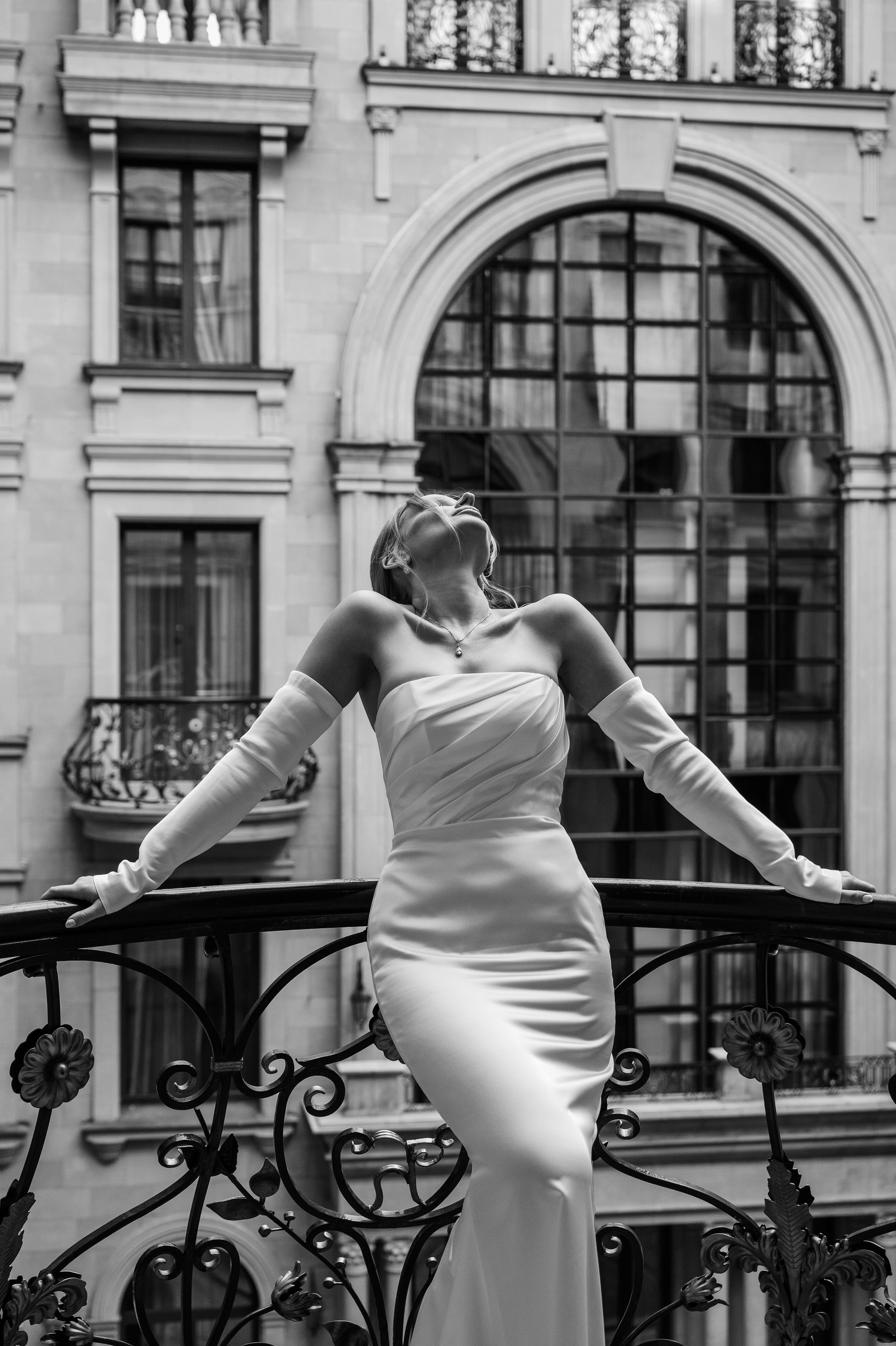 Жених и невеста одевают обручальные кольца на фоне свадебной арки с цветами.