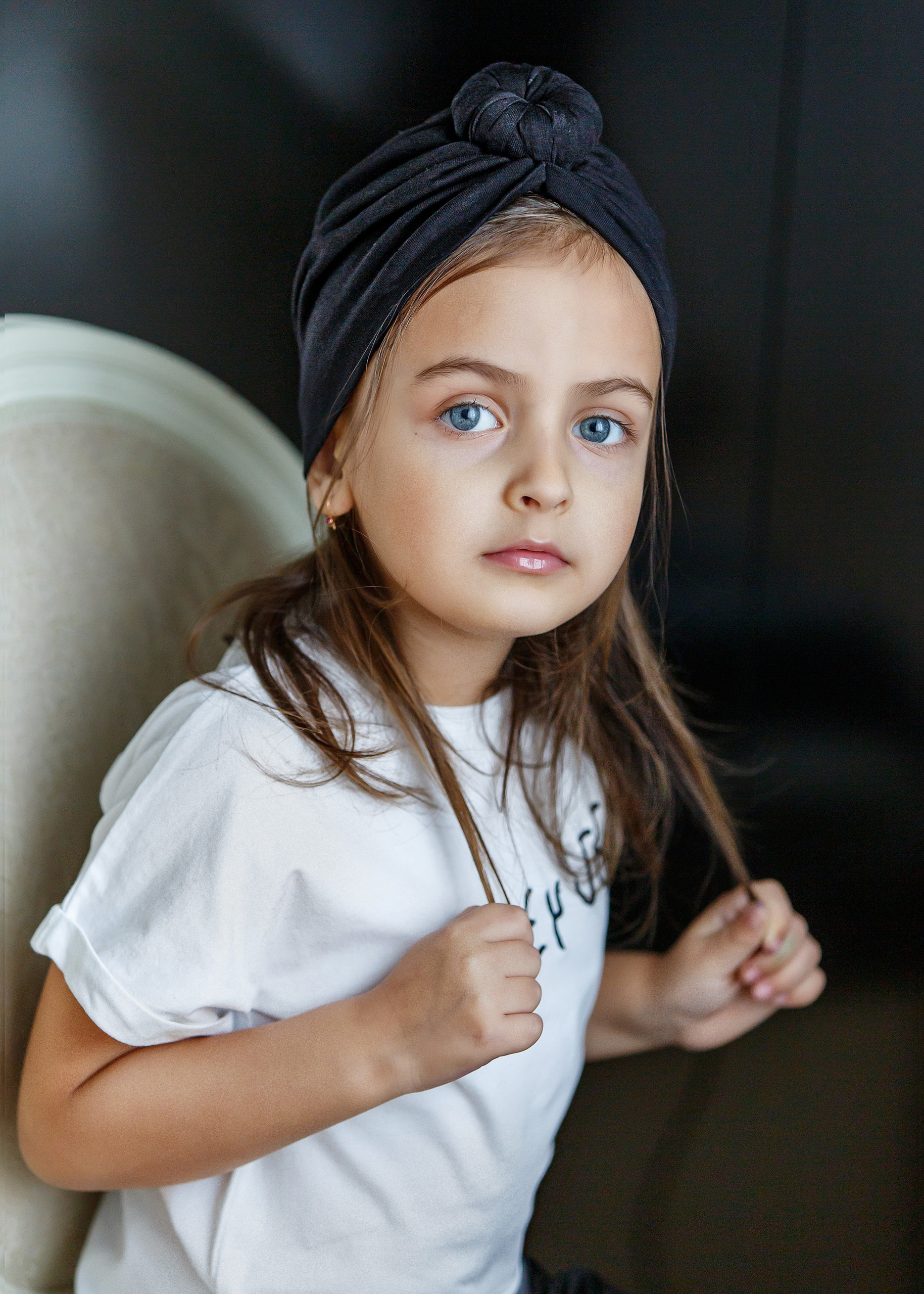 девочка в белой футболке сидит на стуле