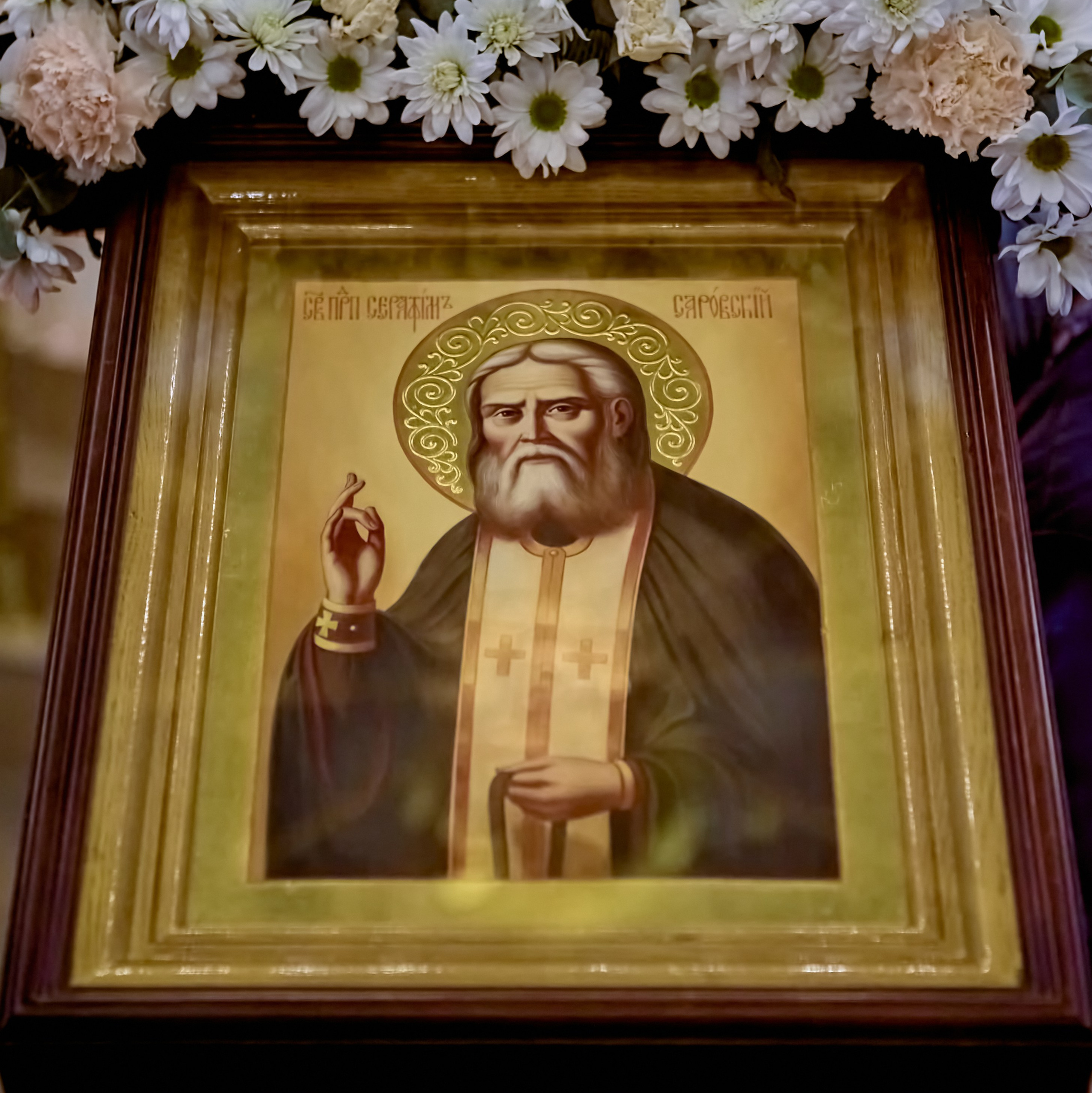 Икона Святаго Преподобного Серафима Саровского лежит на аналое украшена цветами