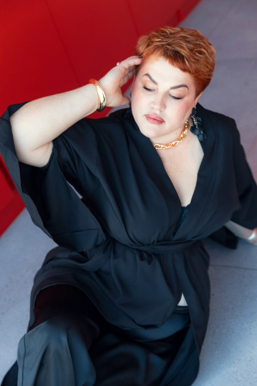 красивая женщина плюс сайз позирует на полу в черном кимоно