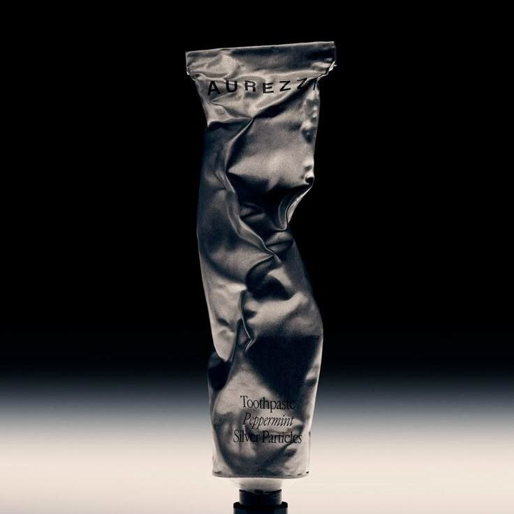 Металлический мятый тюбик крема на тёмном фоне