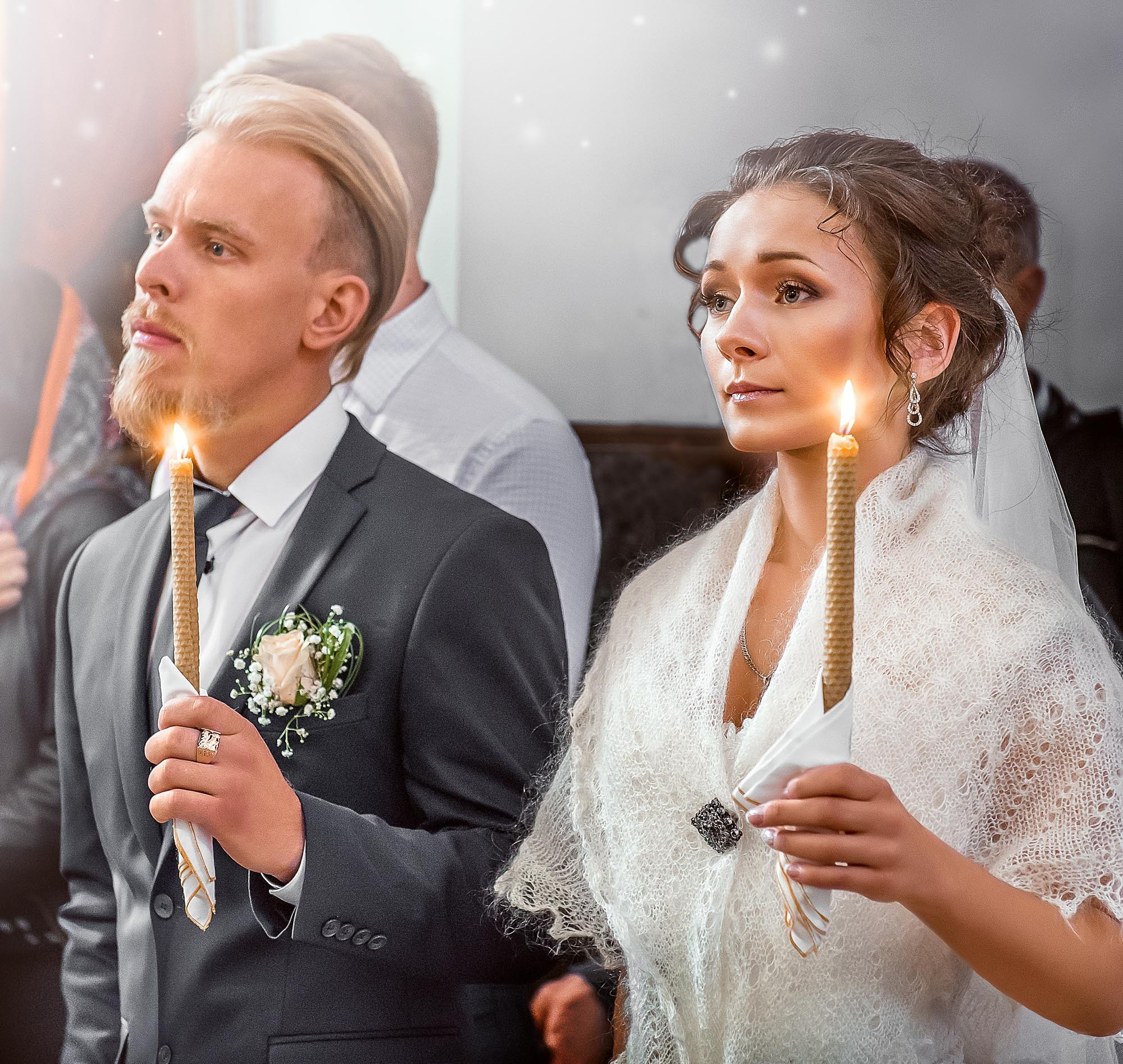 парень и девушка стоят в церкви держат в руках зажженные свечи, идет обряд венчания