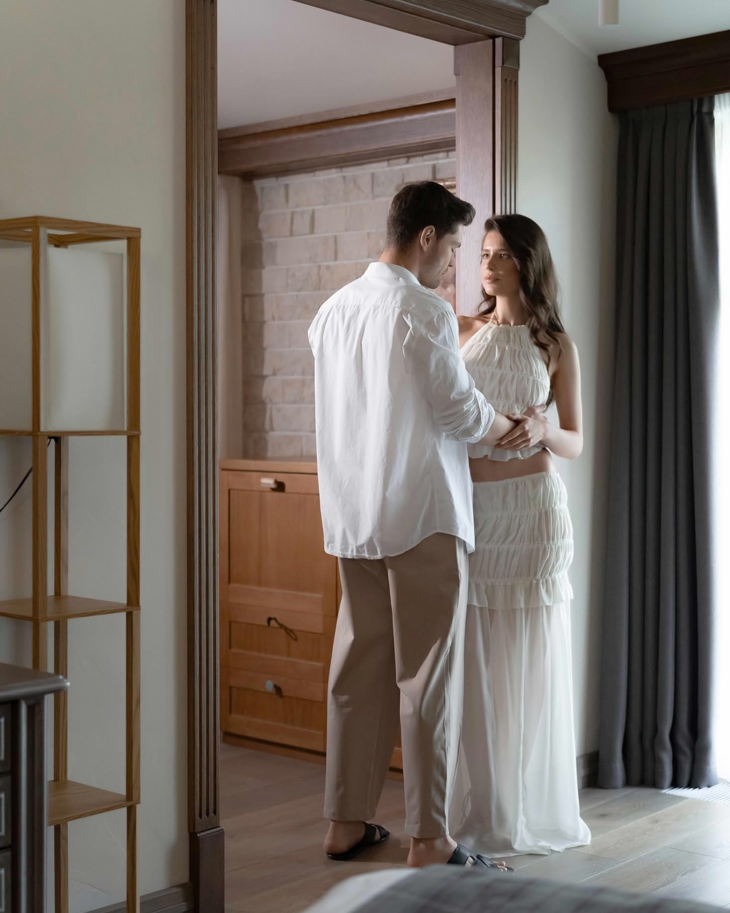 Жених и невеста обнимаются в дверном проёме гостиничного номера утром свадьбы