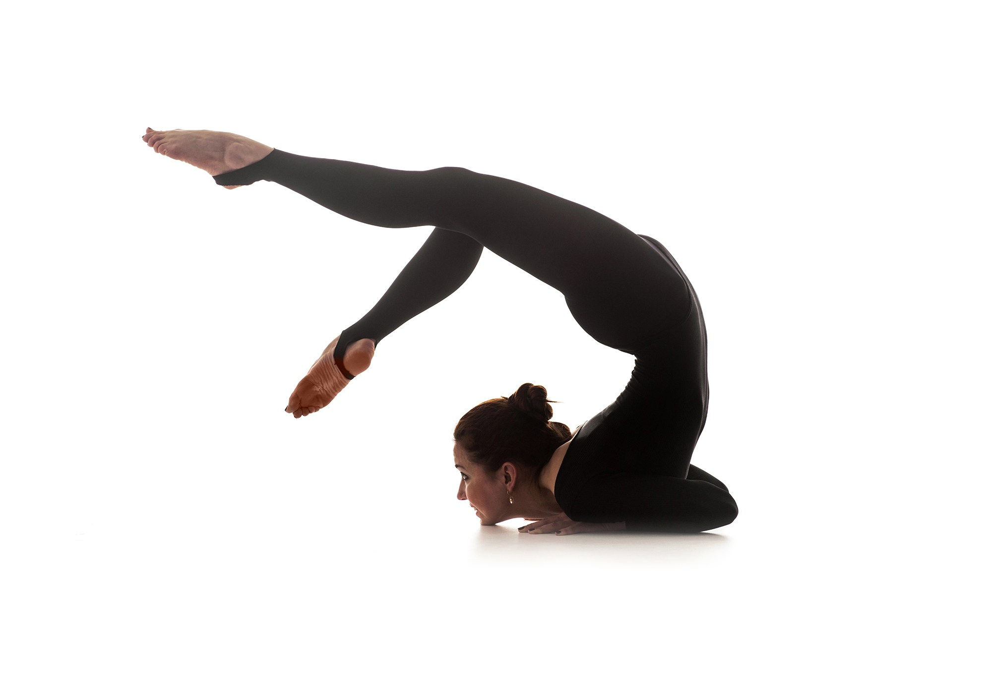 Гимнастка в глубокой гибкой позе, выполняющей прогиб назад с плотной группировкой корпуса. Художественная спортивная съёмка гибкости — Москва и Истринский район