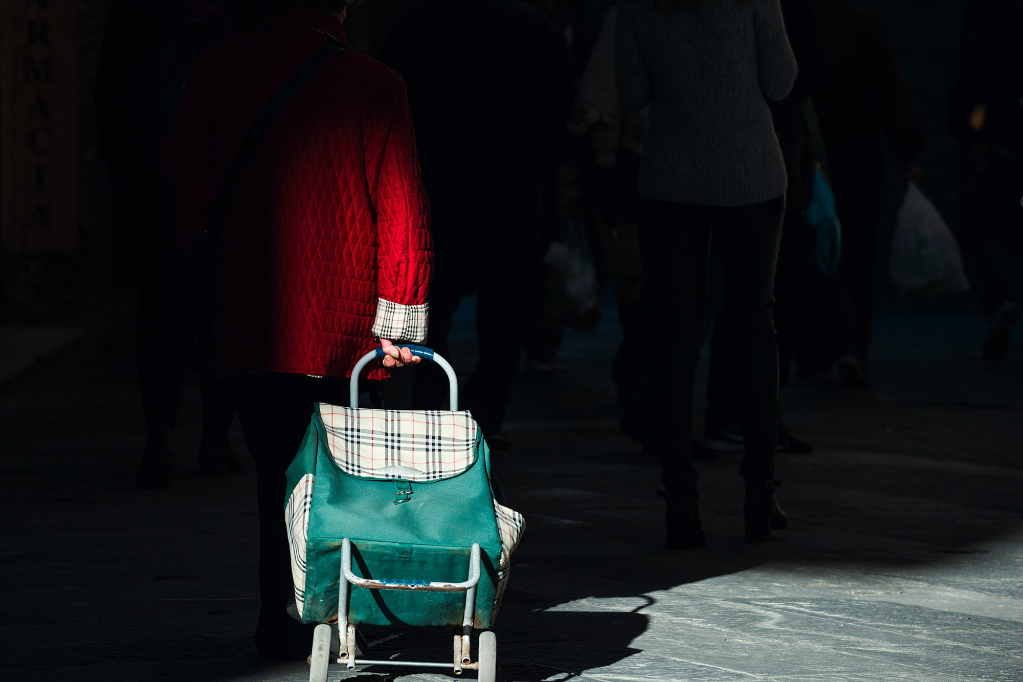 Человек с красной сумкой на колесиках, контровой свет солнца — красная деталь в городской фотографии | Talulla