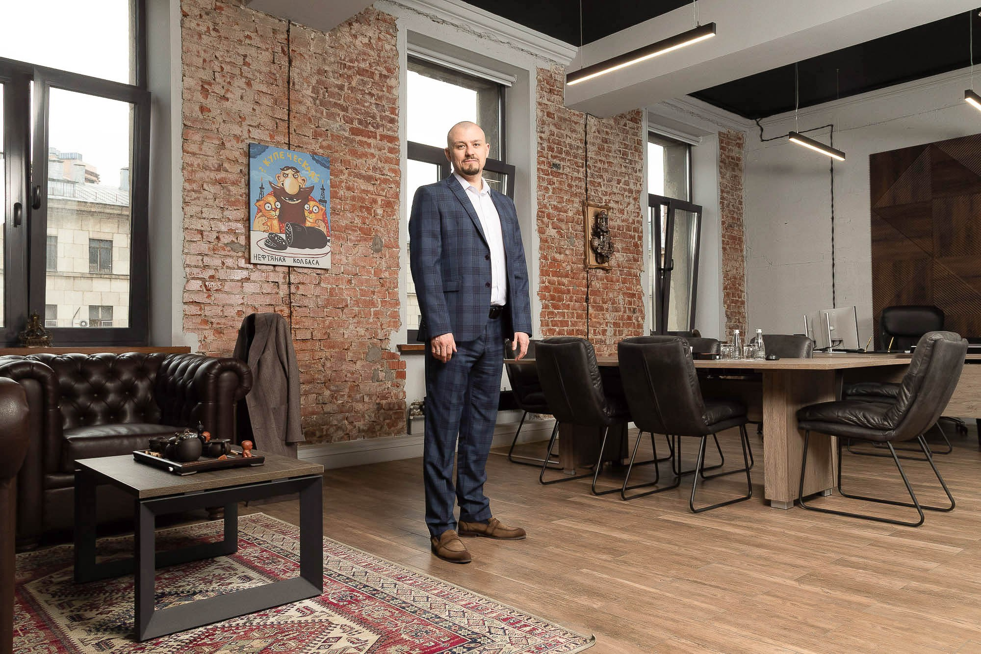 Мужчина в деловом костюме и галстуке позирует в стильном интерьерном пространстве — фотосъемка для бизнес-портрета.