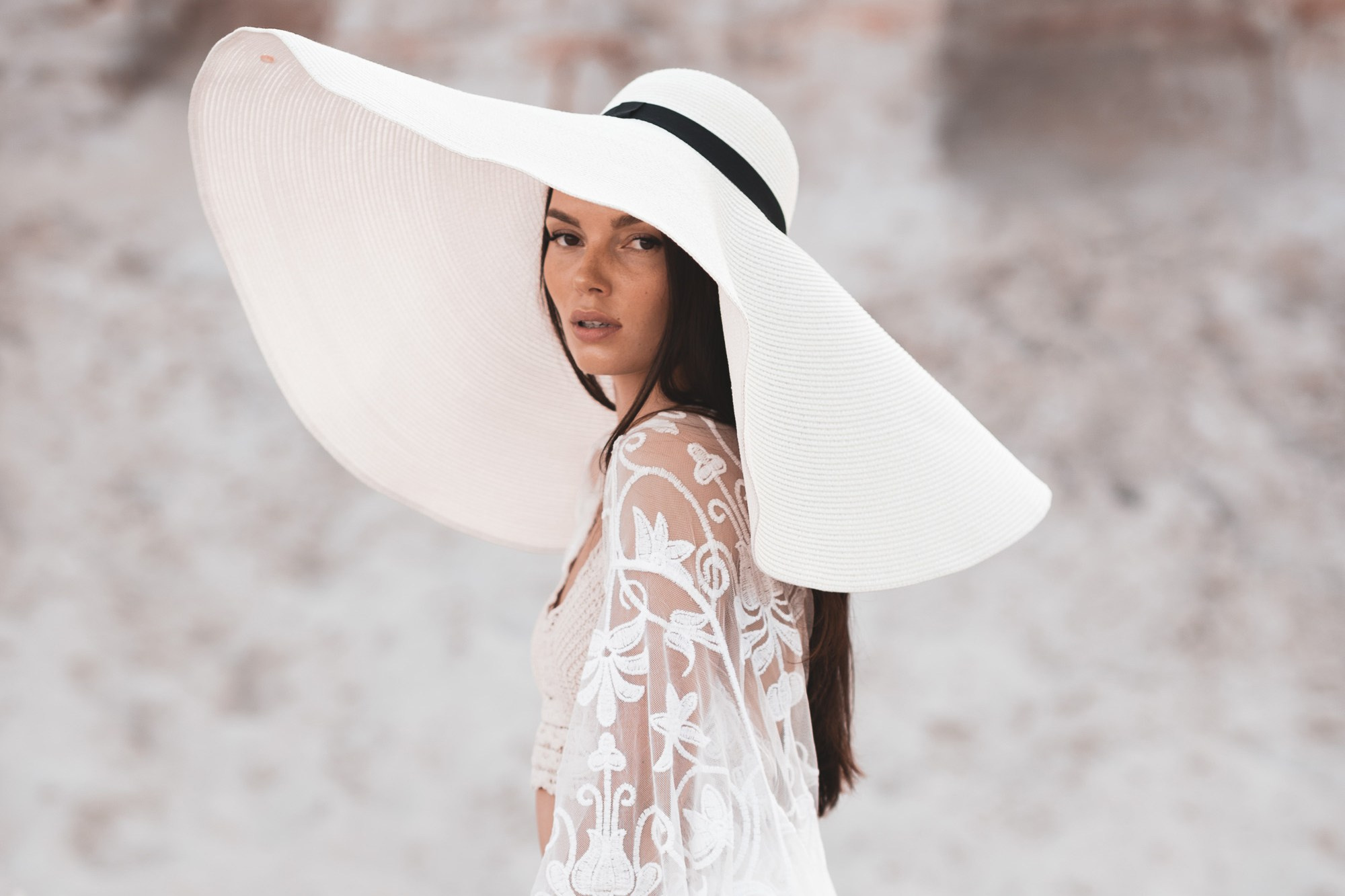 Красивая девушка в светлой шляпе с огромными полями в песчаном карьере