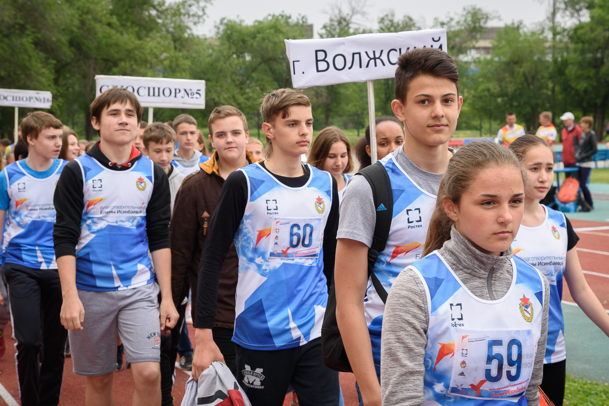 Участники соревнований стоят на беговой дорожке стадиона