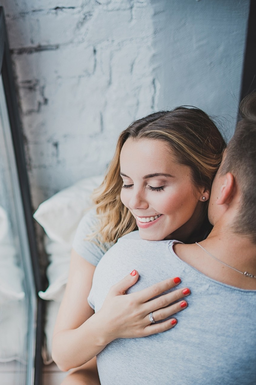 Фото любящей пары обнимается у окна в светлой комнате