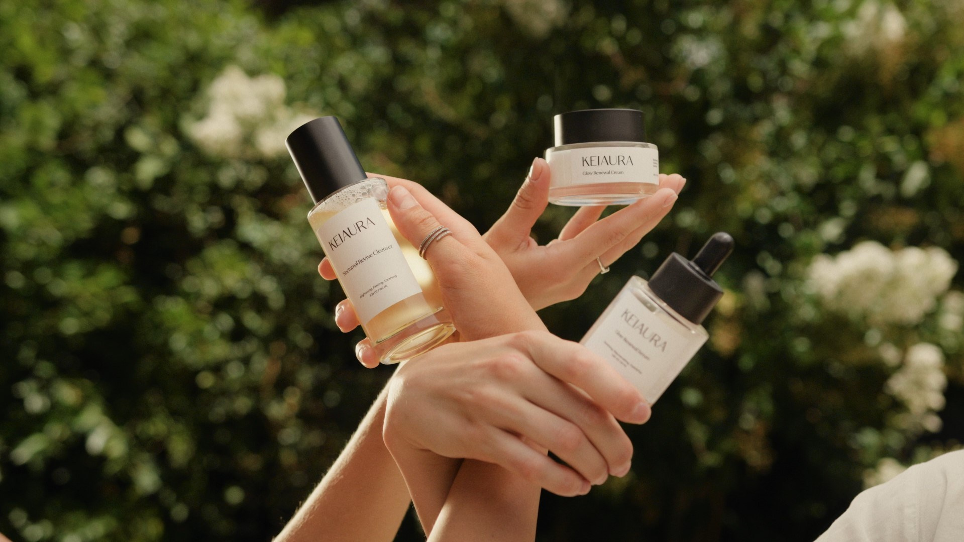 Hands holding luxury skincare products against a natural green background, symbolizing premium beauty.