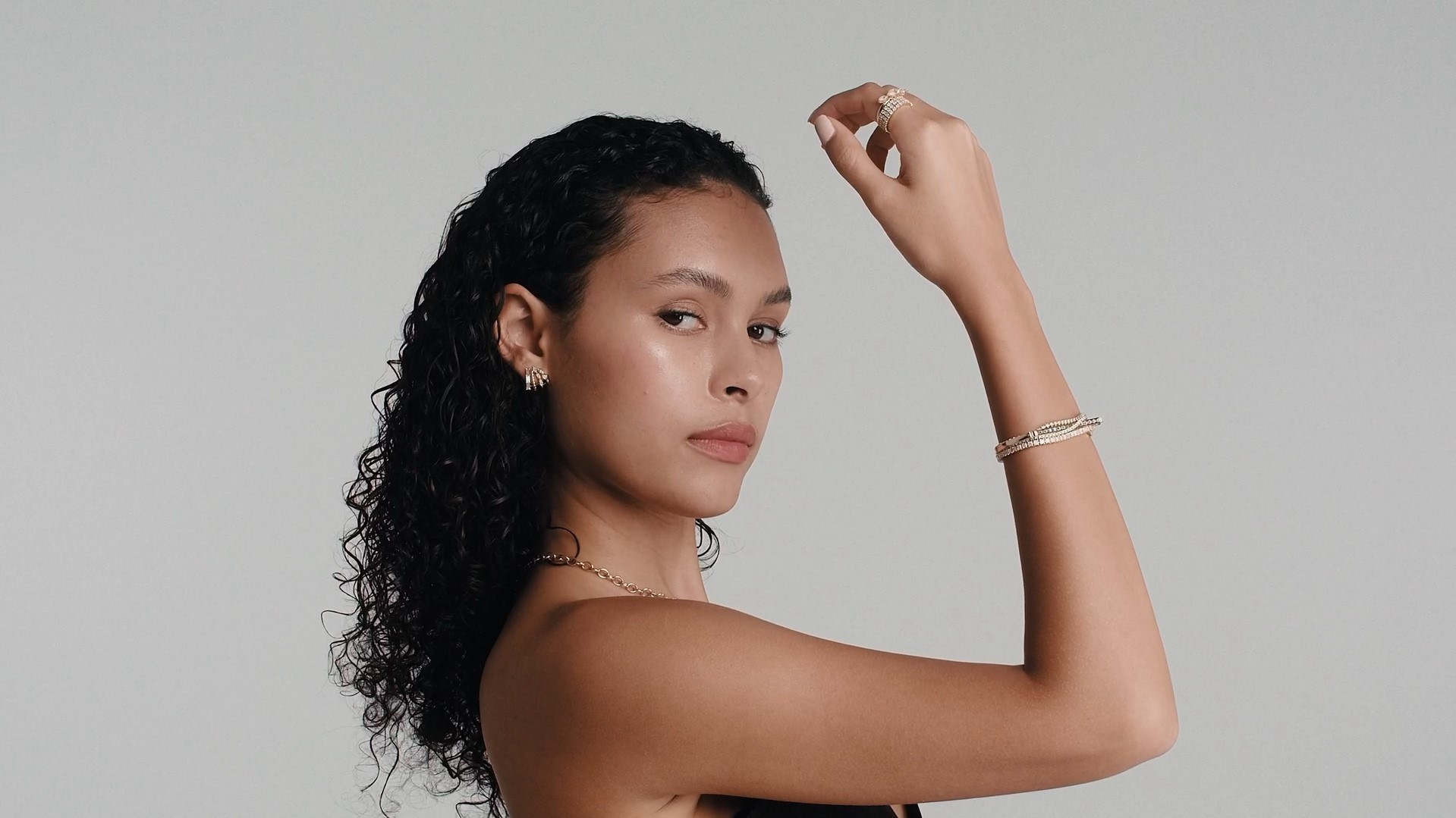 Elegant model posing with gold jewelry, highlighting luxurious fashion accessories.