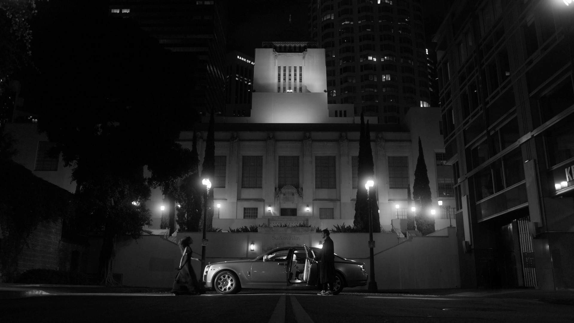 Nighttime black and white view of Los Angeles Central Library in downtown, a historic landmark and popular video shoot location, with a luxury car in the foreground.