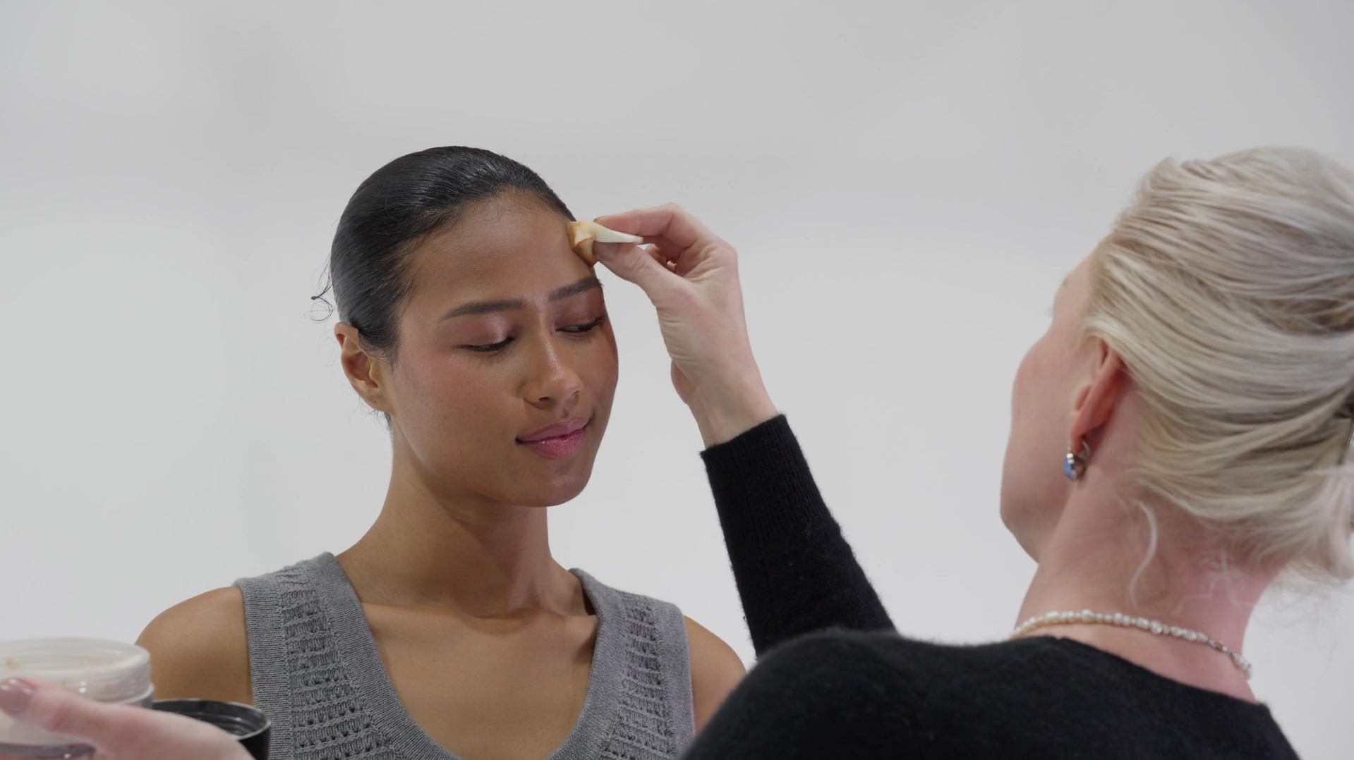 Makeup artist applying foundation to a model during a New Vanity branding video shoot, emphasizing professional beauty techniques and artistry.