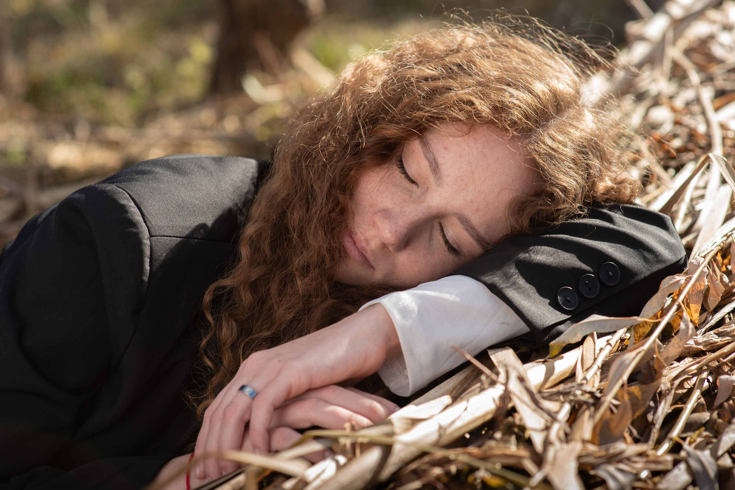 Крупным планом лицо спящей девушки с веснушками на сухой траве