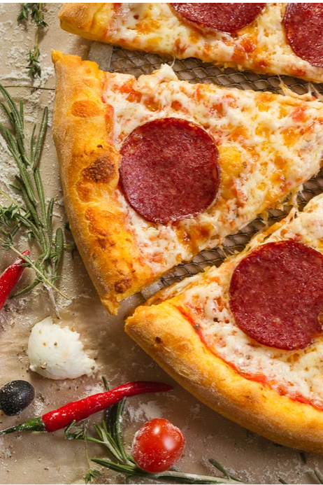 Сочная пицца пепперони лежит на столе окруженная красным перцем и розмарином