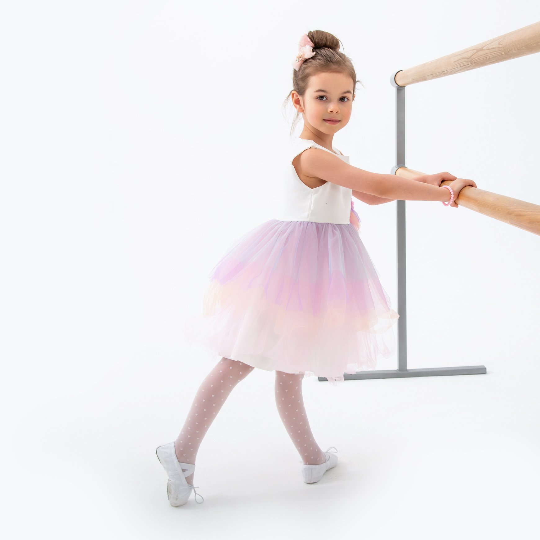 Девочка балерина позирует у станка в студии с белой циклорамой на фотосессии для гимнастики и балета от фотографа Галины Шараповой