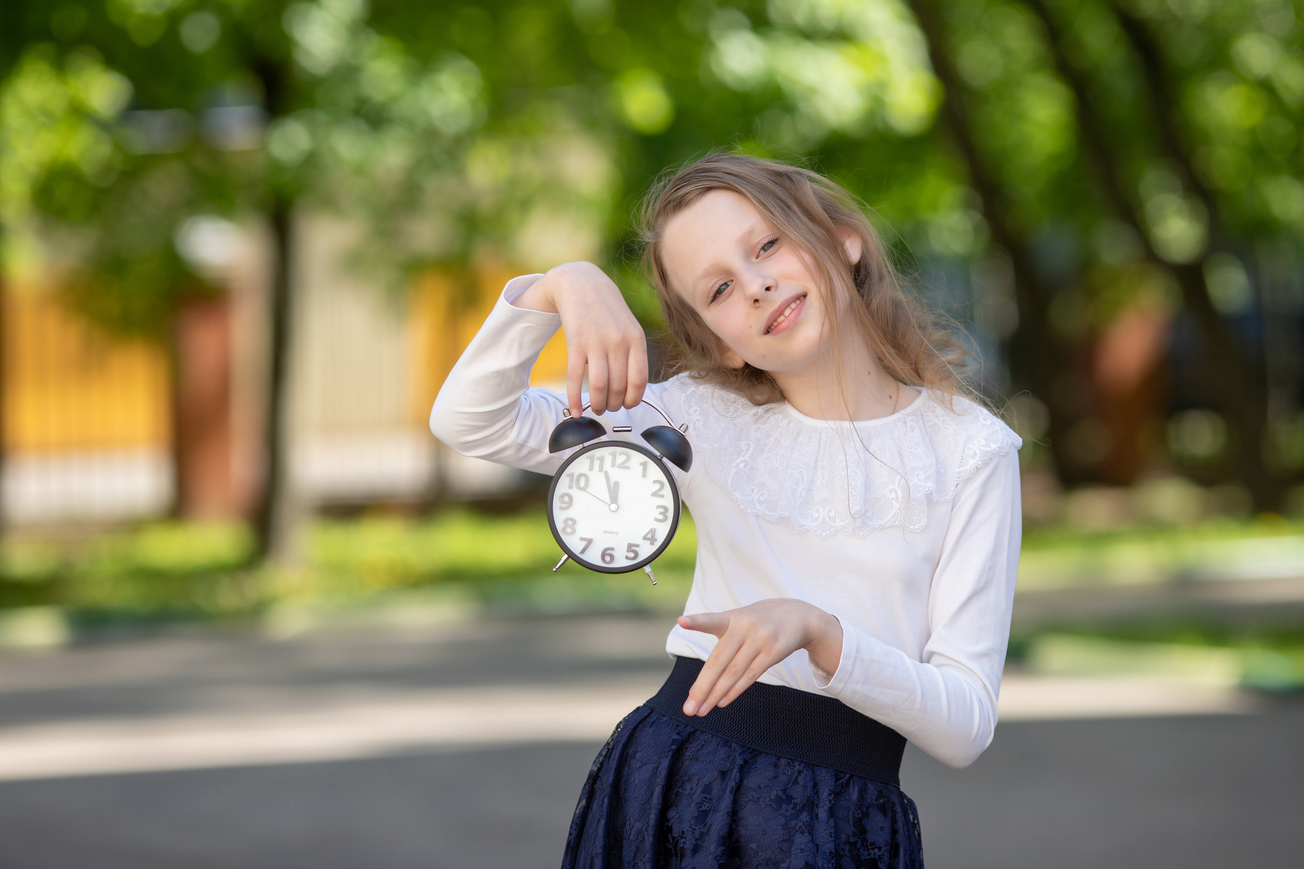 Школьница с будильником на фотосессии для выпускного альбома