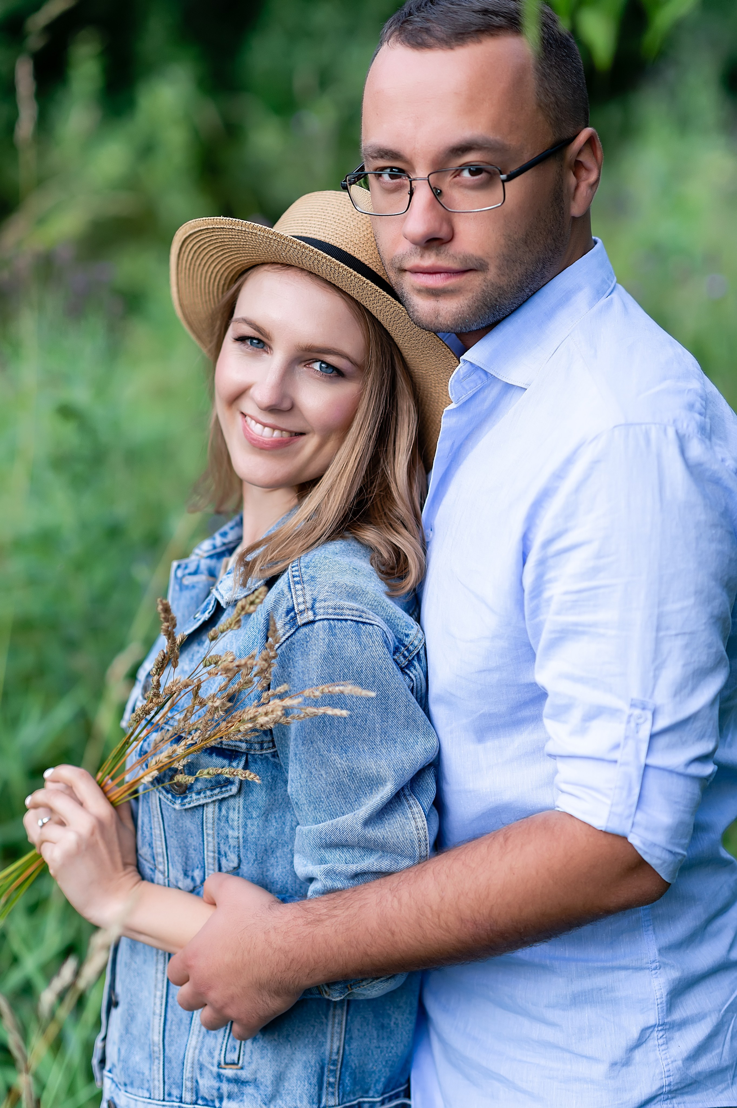 фотография, на которой двое влюбленных стоят обнявшись, и девушка держит в руках несколько травинок